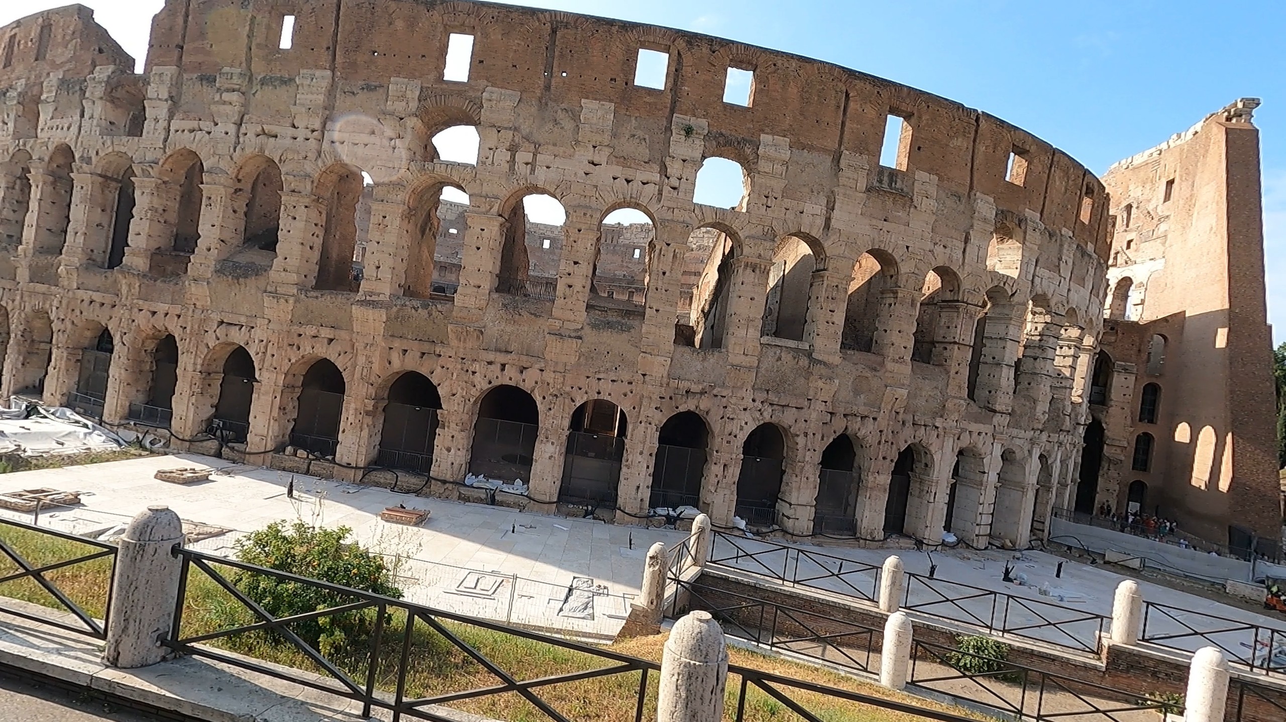 The Roman Colosseum exterior in early morning light with mostly empty grounds in front