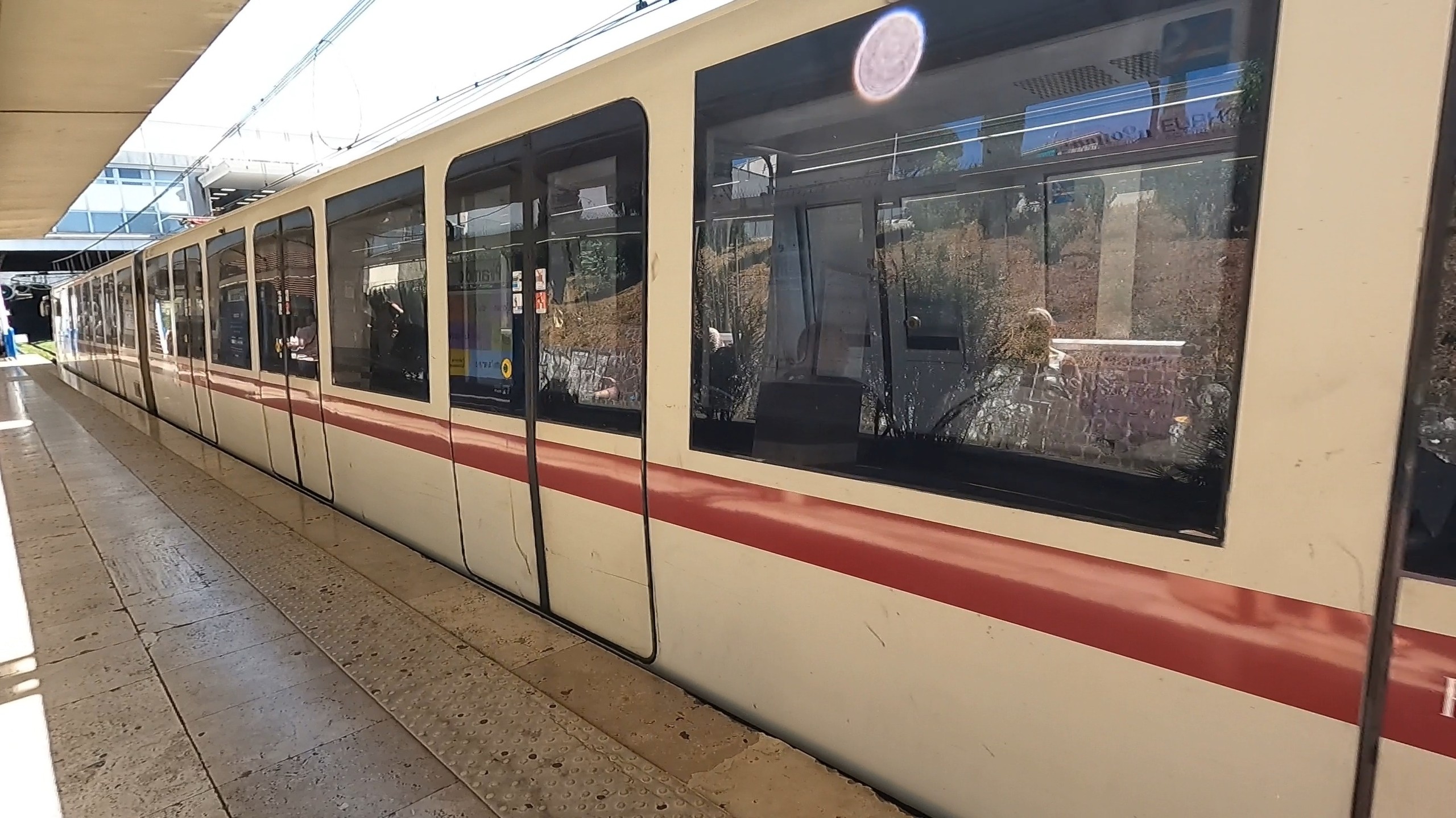 A Rome metro train, white with red stripe livery, waiting at a station platform