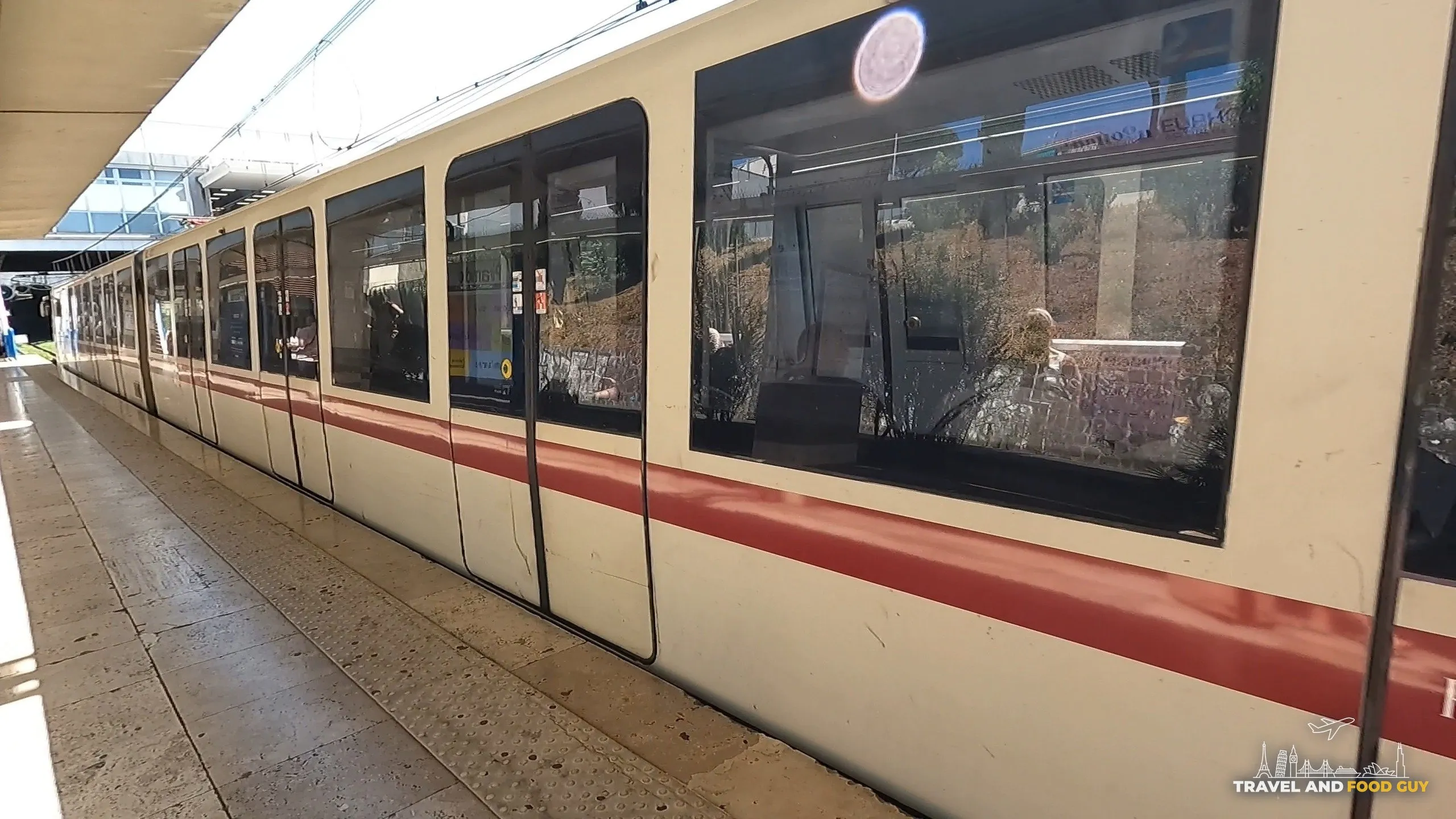 A Rome metro train, white with red stripe livery, waiting at a station platform