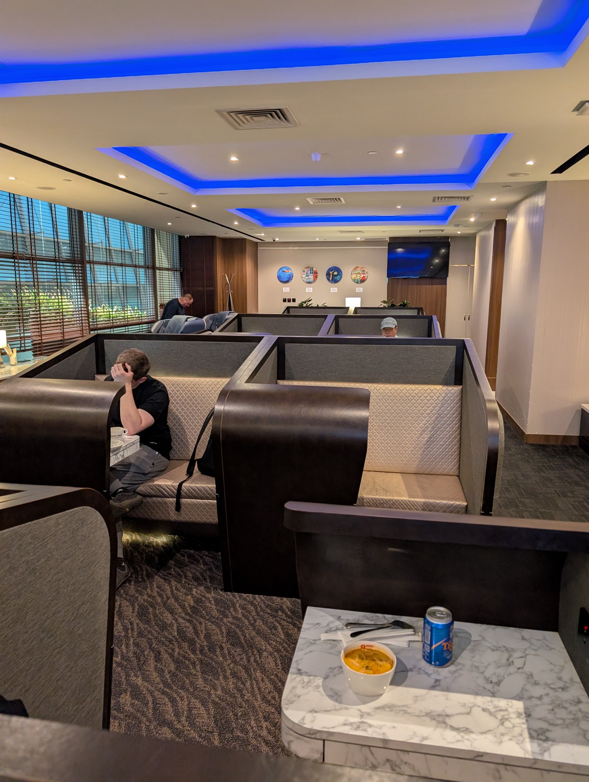 Private nook booths under blue cove lighting at the SATS Premier Lounge Changi T2