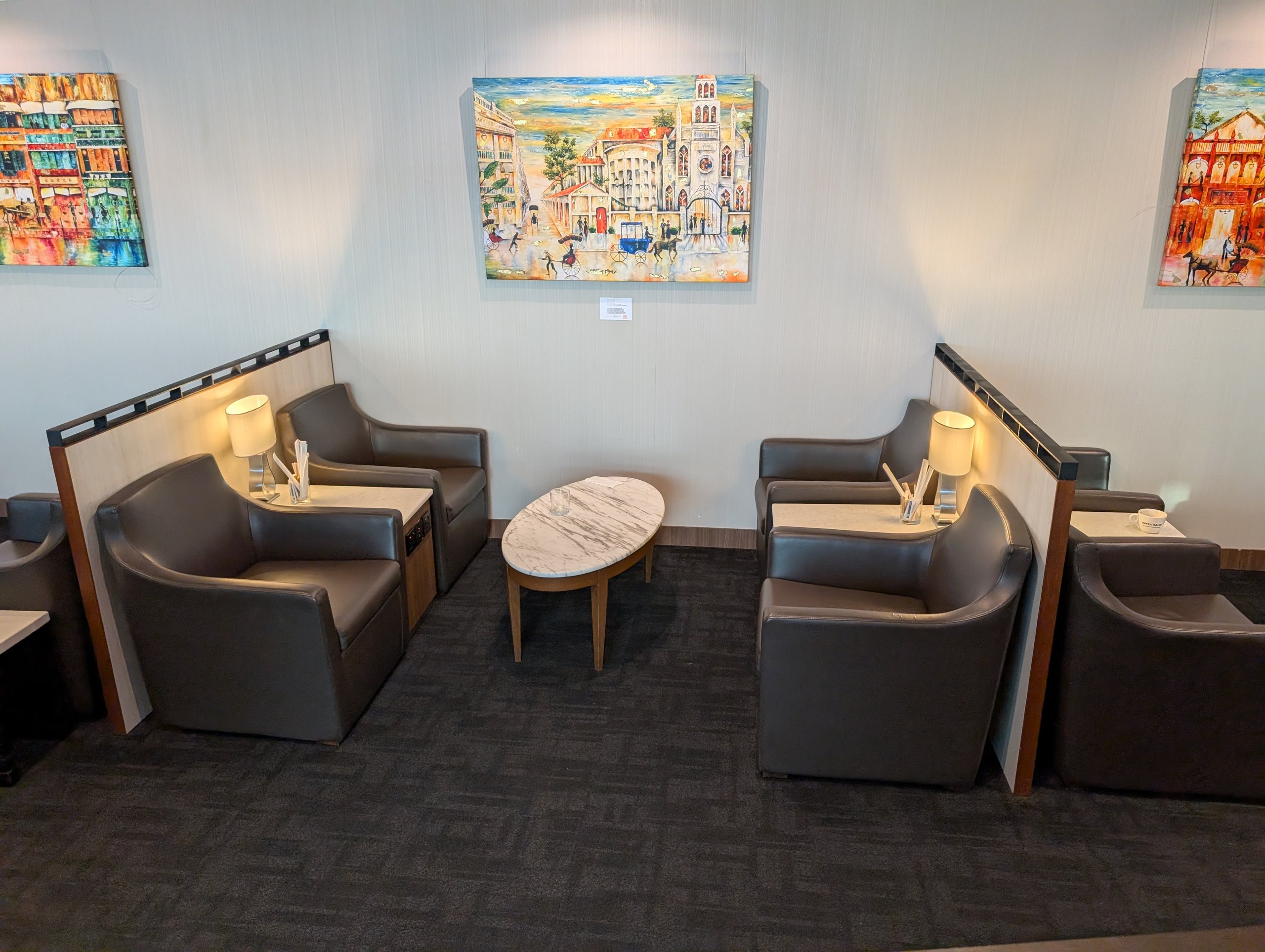 Quiet seating area with cityscape paintings on the walls at the SATS Premier Lounge Changi T2