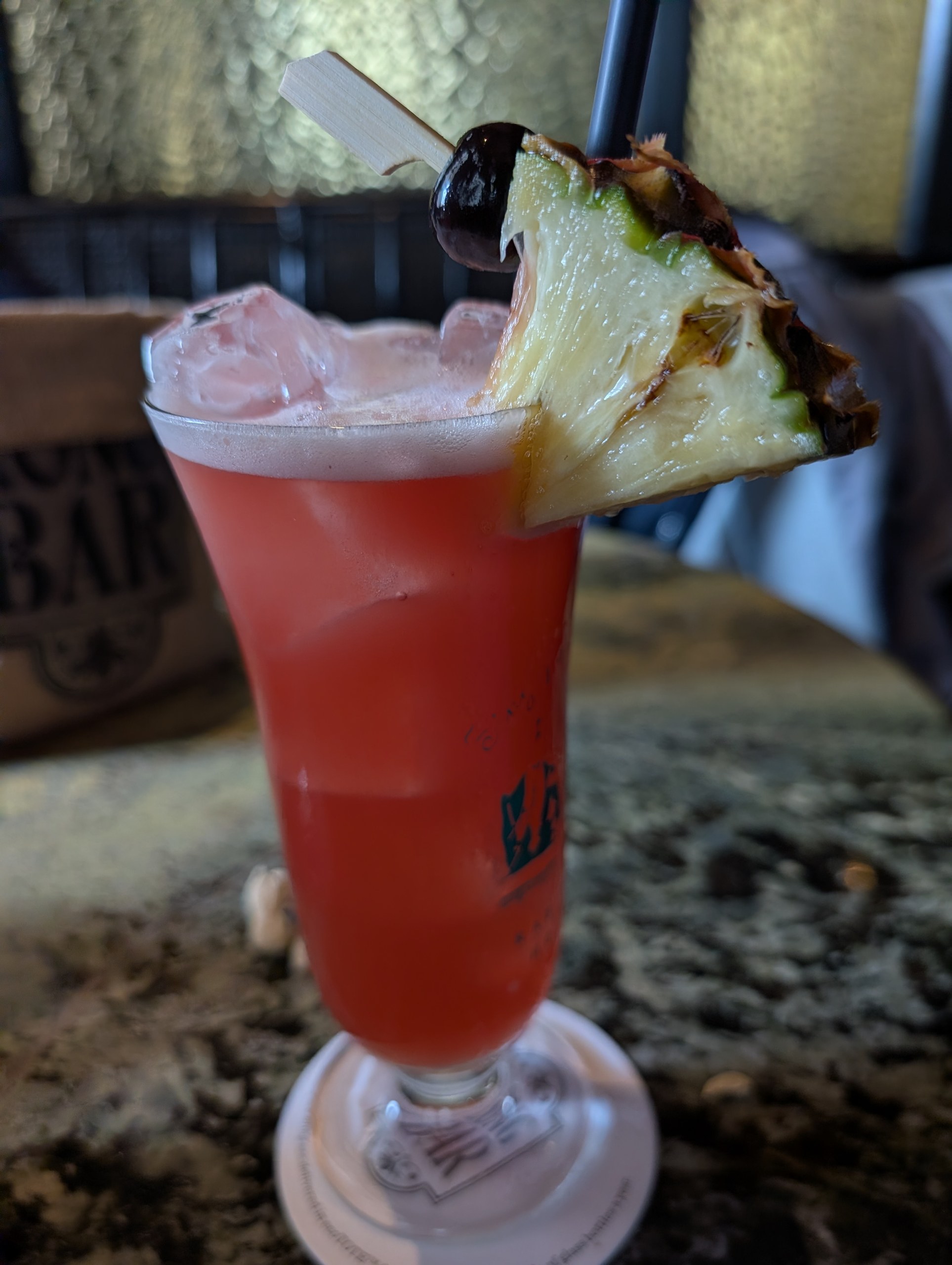 The original Singapore Sling at Long Bar in a branded hurricane glass with a pineapple wedge and cherry garnish