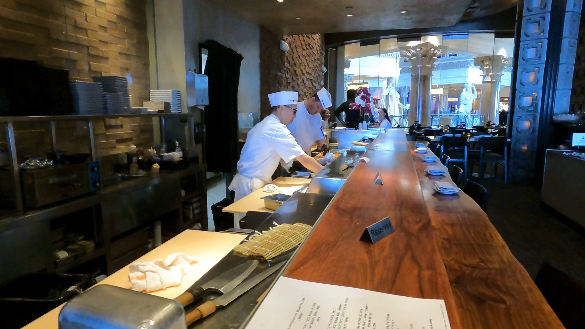Two sushi chefs working behind the long live-edge wood counter at Sushi Roku Las Vegas