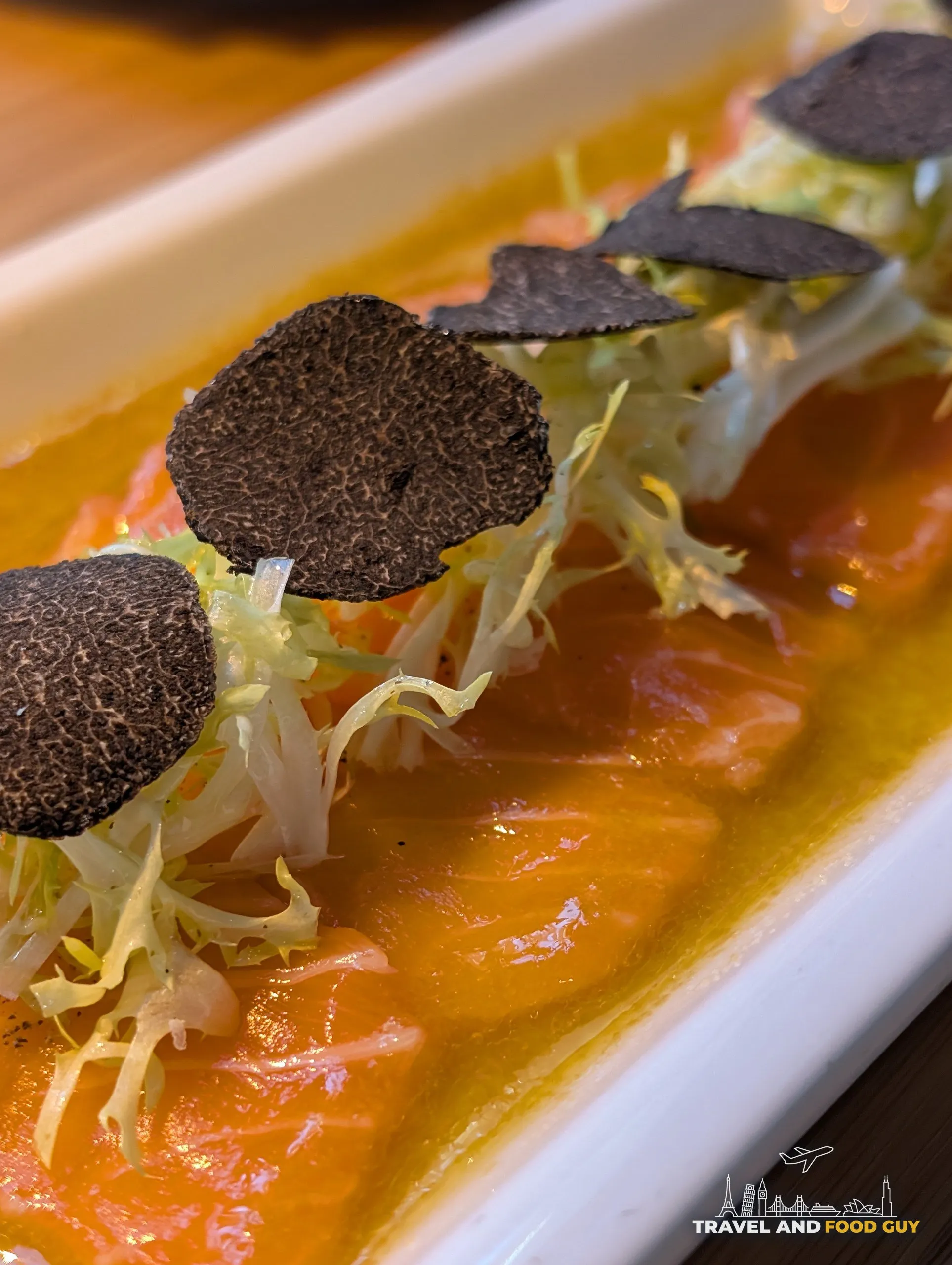 Salmon Truffle Carpaccio at Sushi Roku Las Vegas with thinly sliced salmon, frisée, large black truffle rounds, and citrus oil