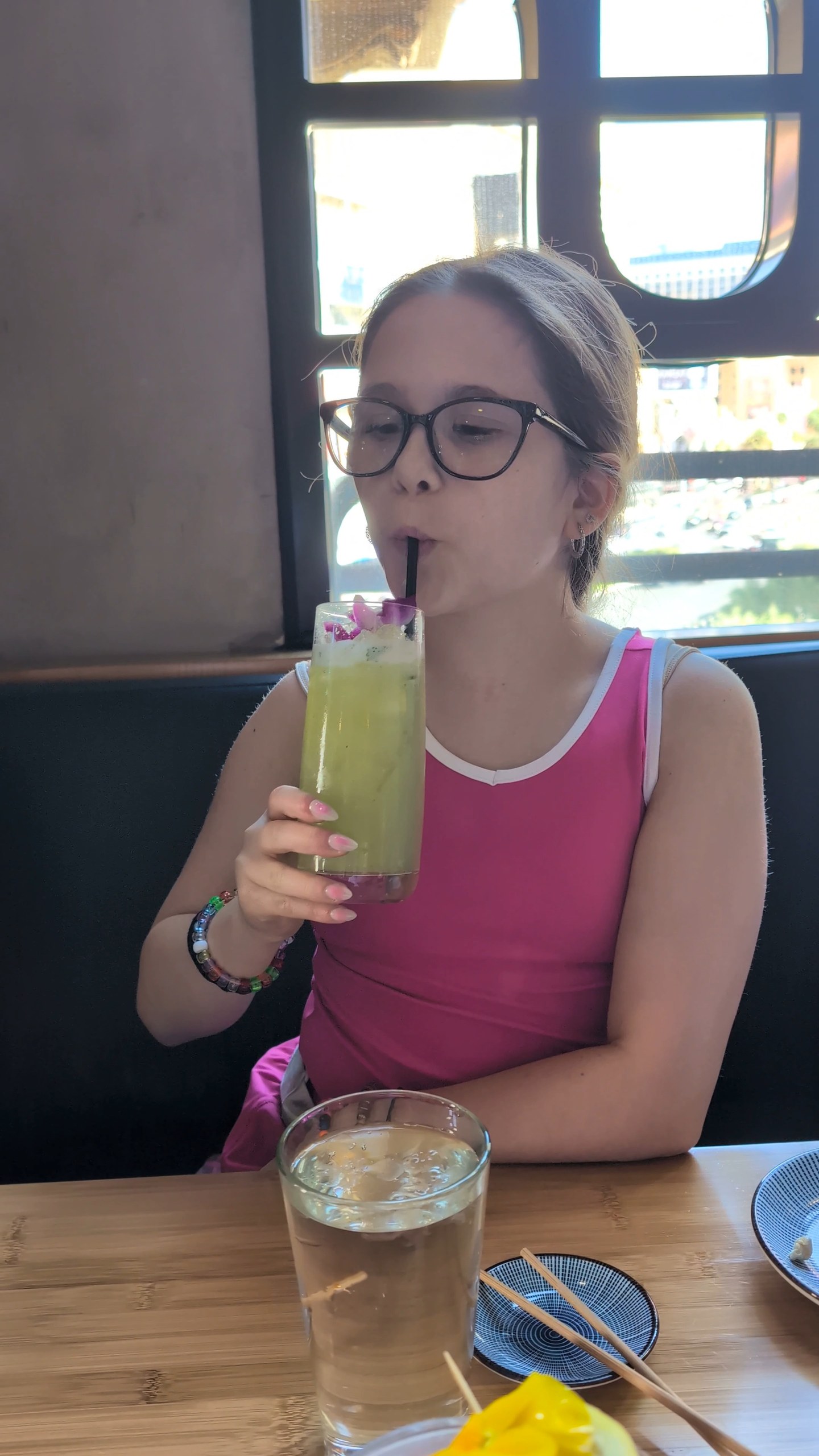 Emily holding the Zen Garden mocktail at the Sushi Roku window table in Las Vegas