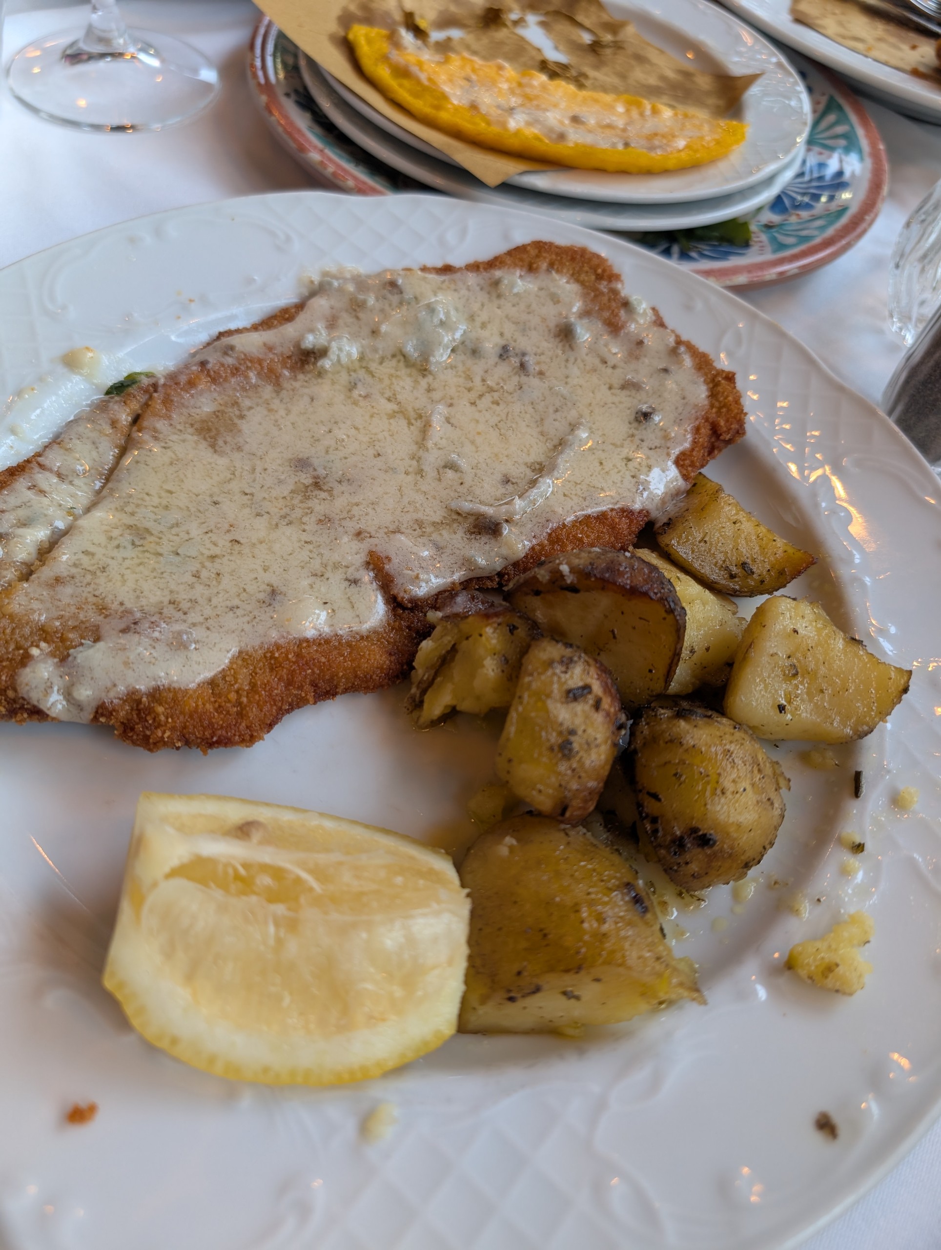 Breaded Milanese-style cutlet covered in truffle cream sauce with golden roasted potatoes and lemon at Trattoria Zà-Zà, Florence