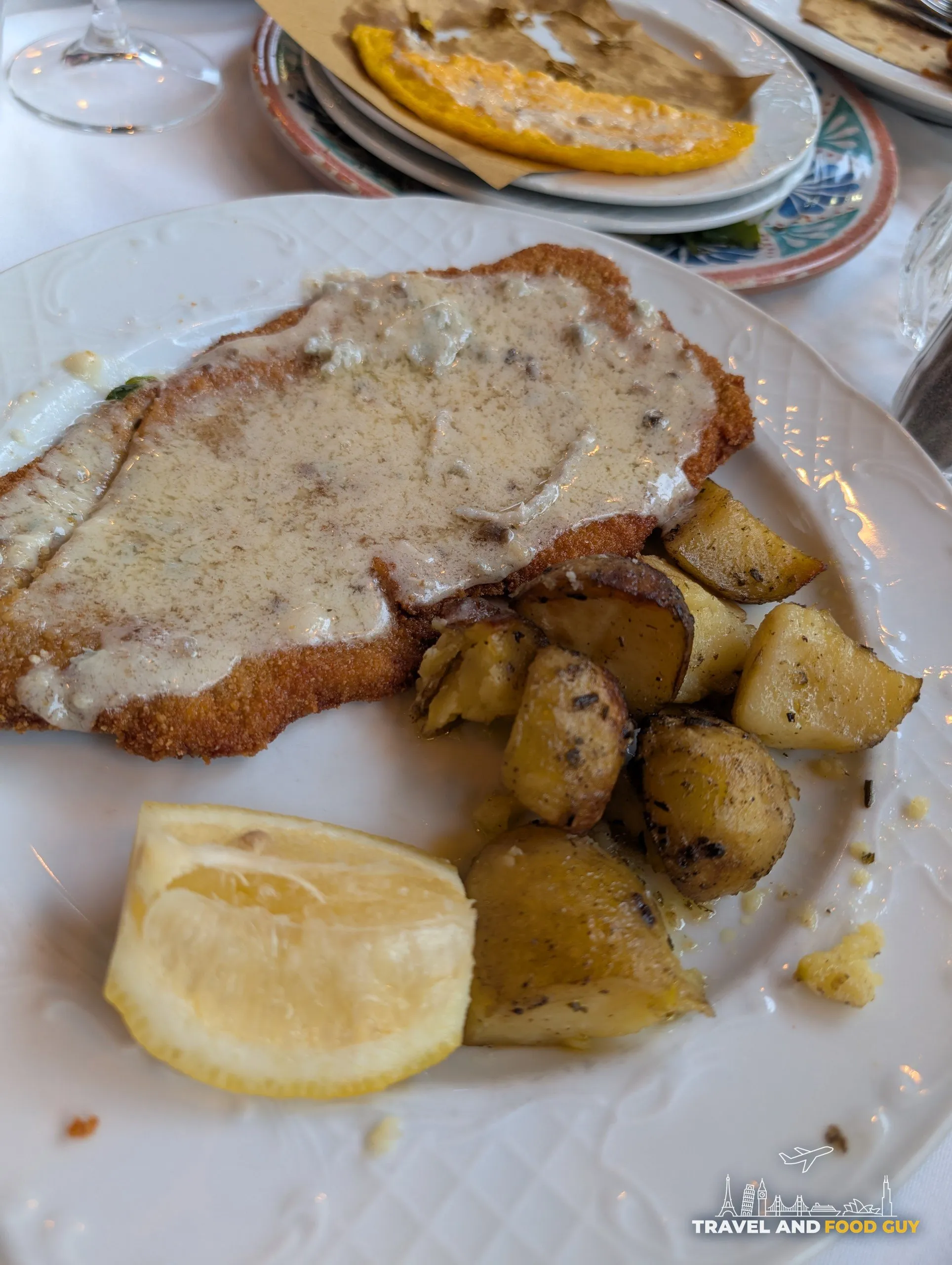 Breaded Milanese-style cutlet covered in truffle cream sauce with golden roasted potatoes and lemon at Trattoria Zà-Zà, Florence