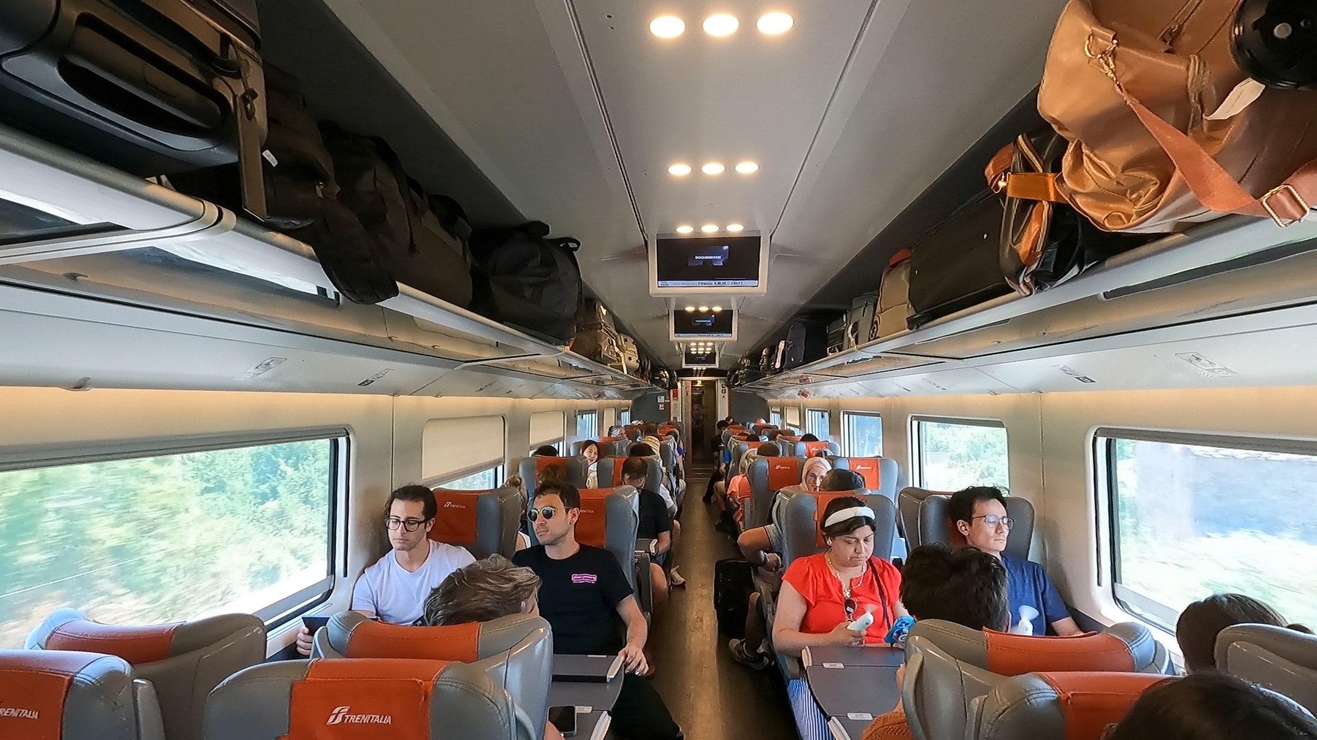 Wide interior view of a Trenitalia Frecciarossa high-speed train cabin with passengers