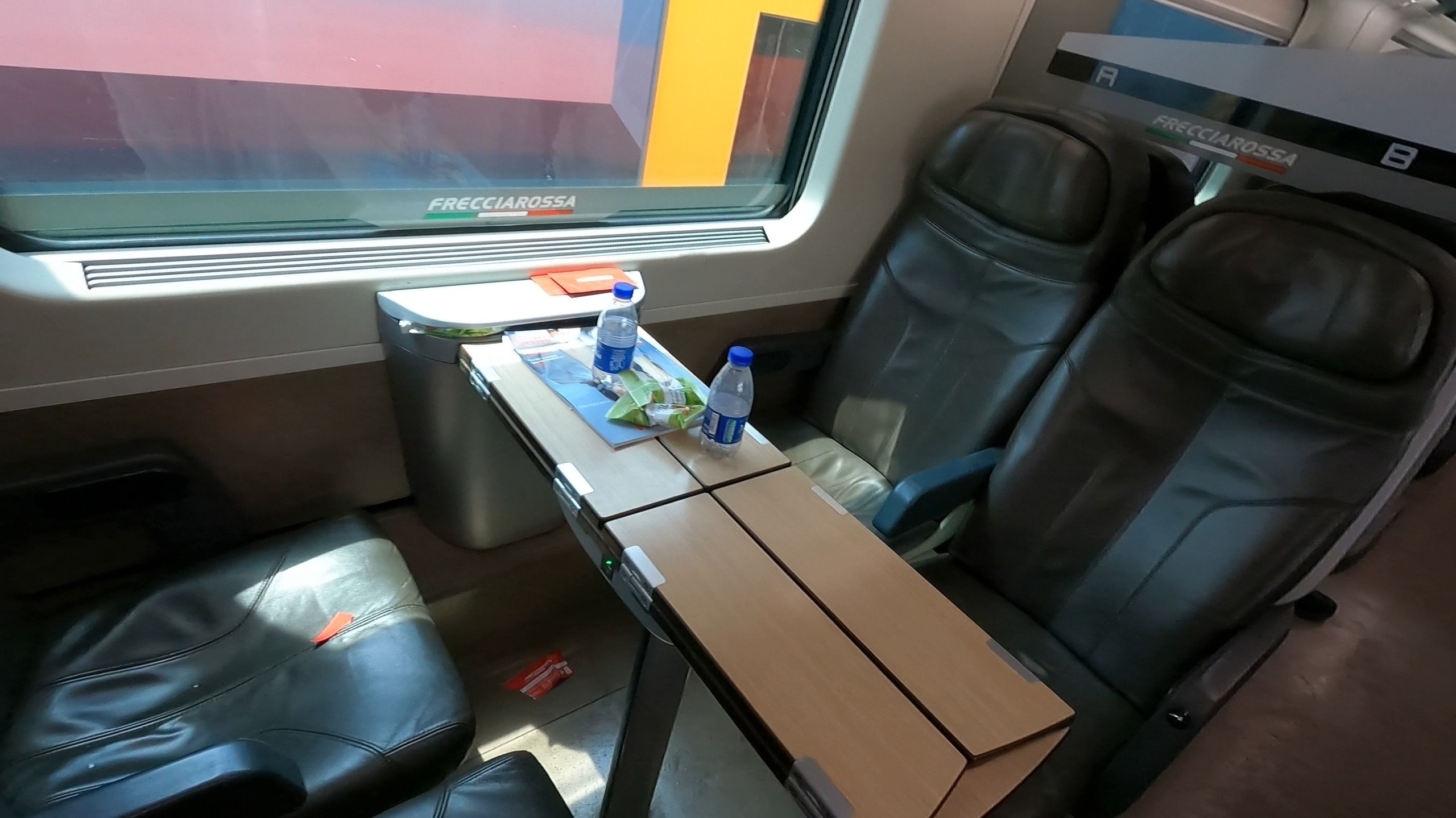 Trenitalia Frecciarossa Premium-class seats with leather upholstery, tray table, complimentary water and a snack package