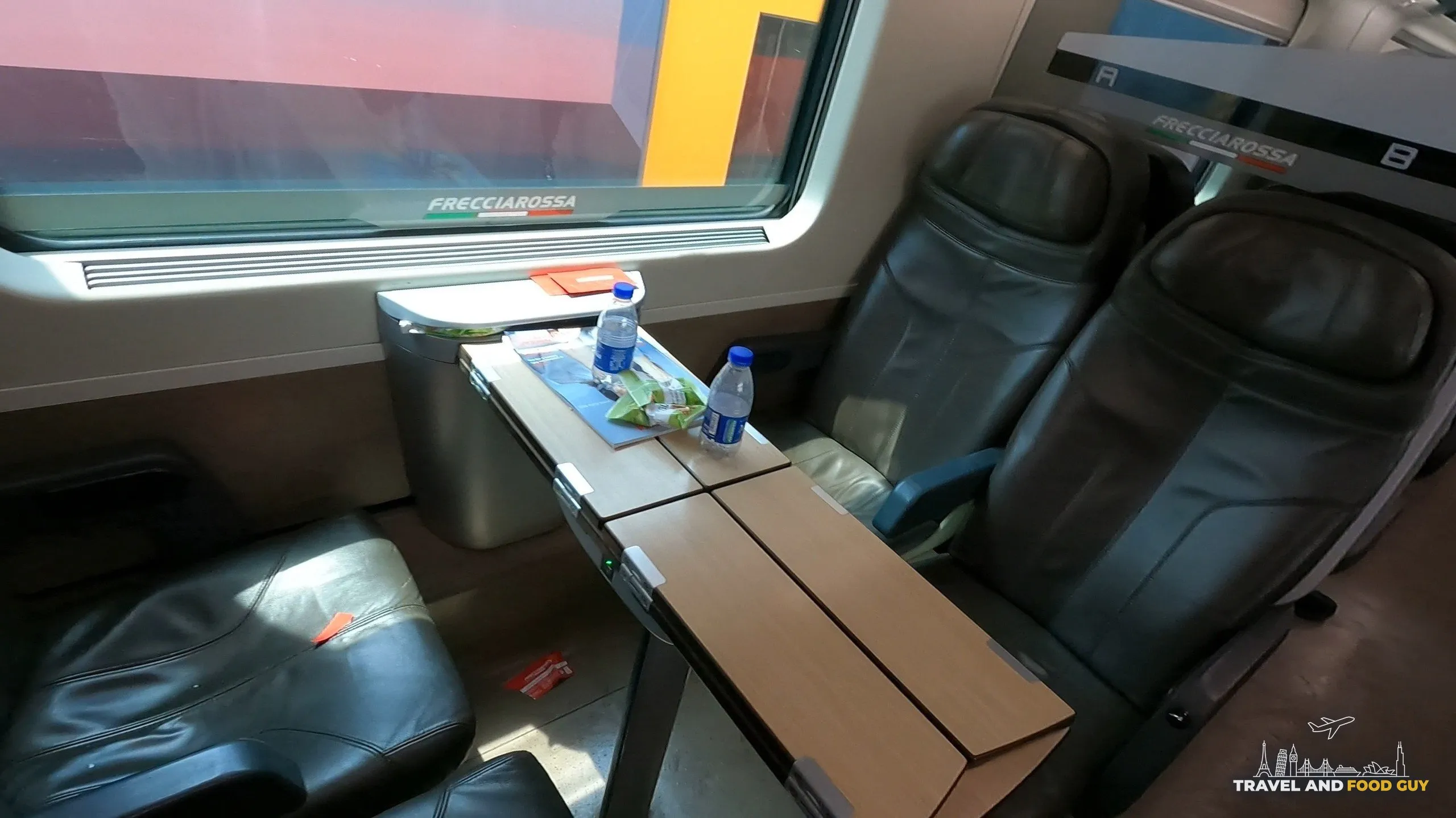 Trenitalia Frecciarossa Premium-class seats with leather upholstery, tray table, complimentary water and a snack package