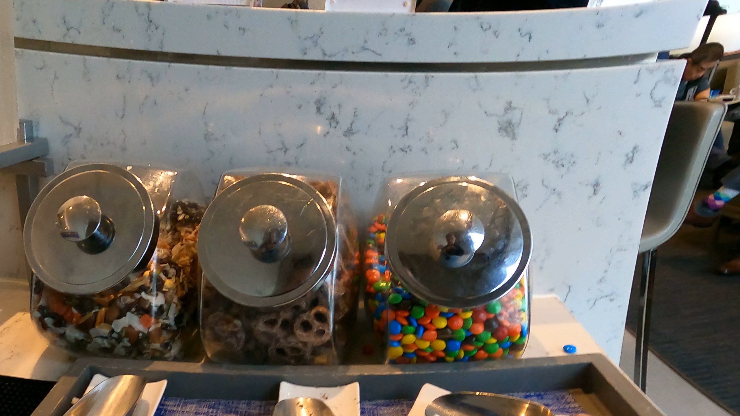 Snack jars of trail mix, chocolate covered pretzels, and M and Ms at the United Club at DFW