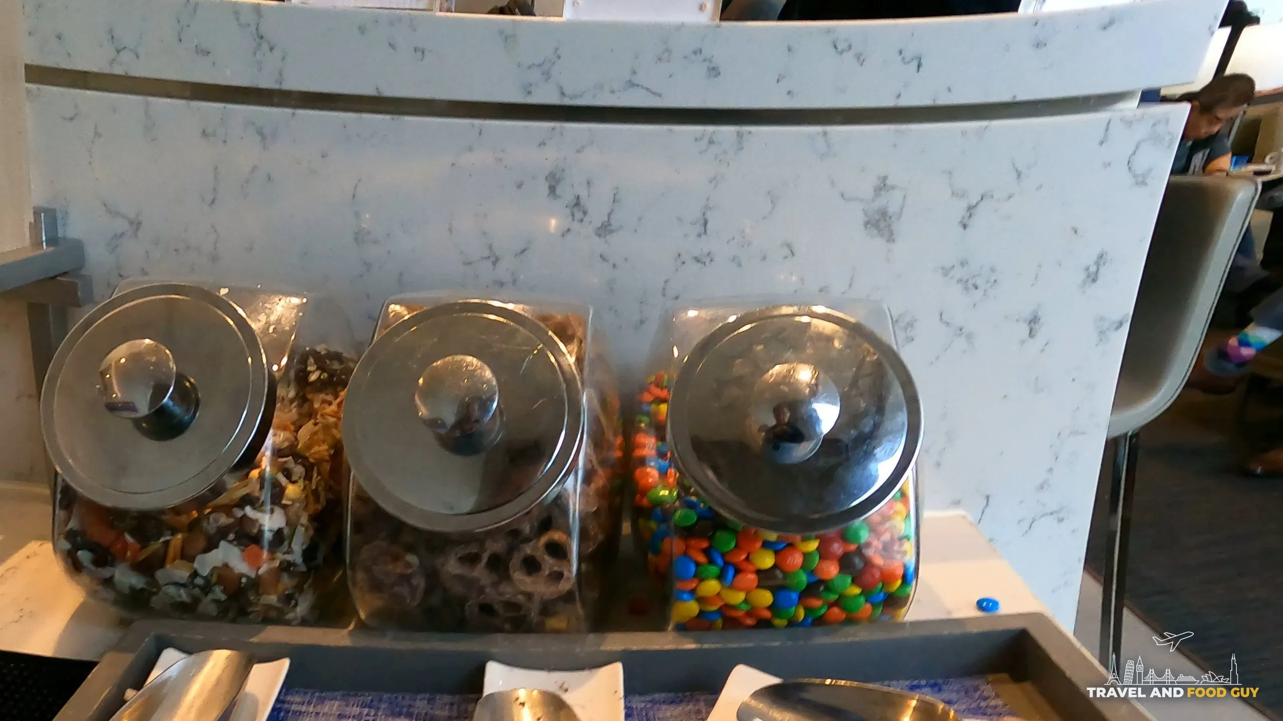 Snack jars of trail mix, chocolate covered pretzels, and M and Ms at the United Club at DFW