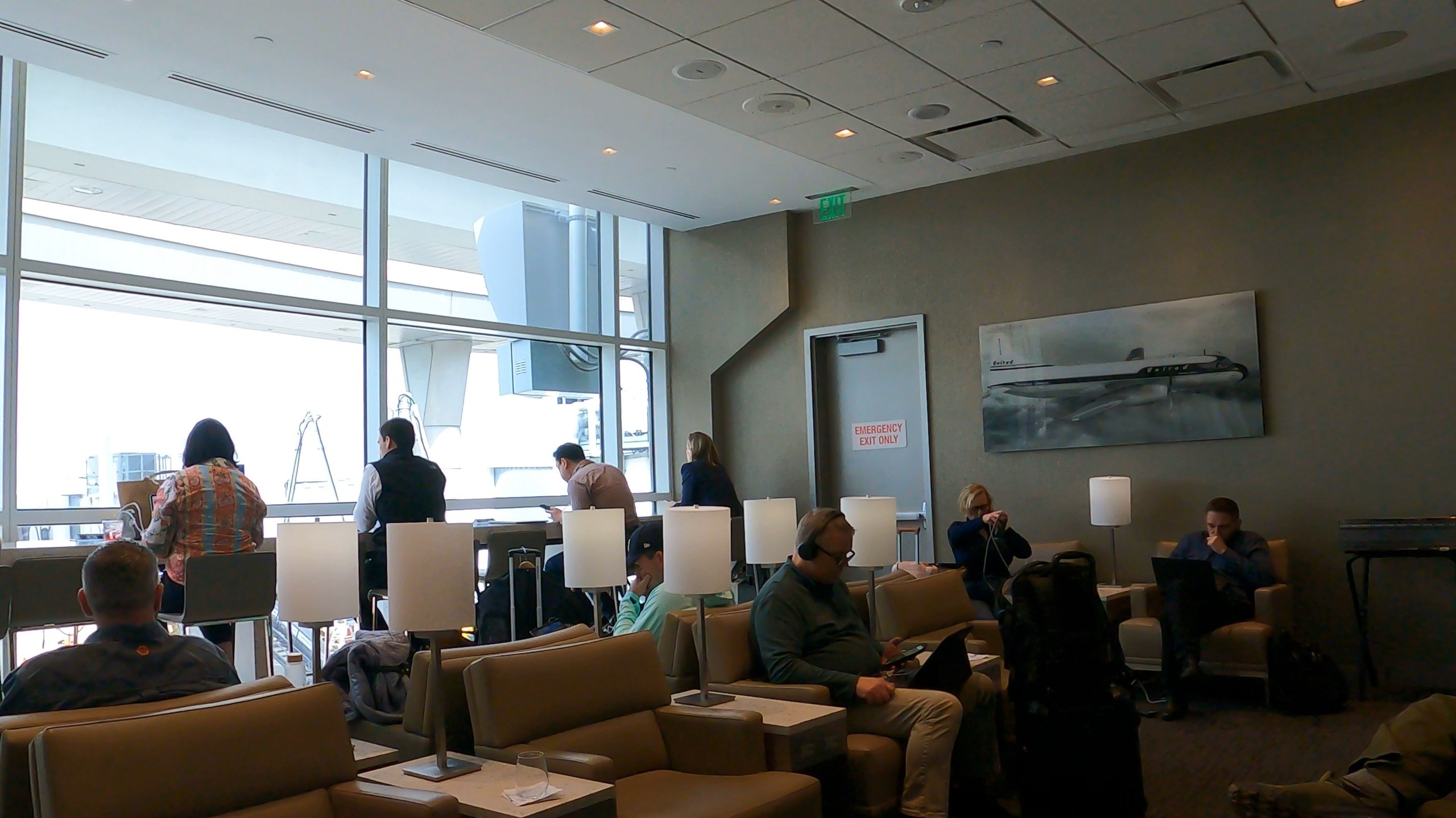 Window seating area at the United Club at DFW with vintage United jet painting