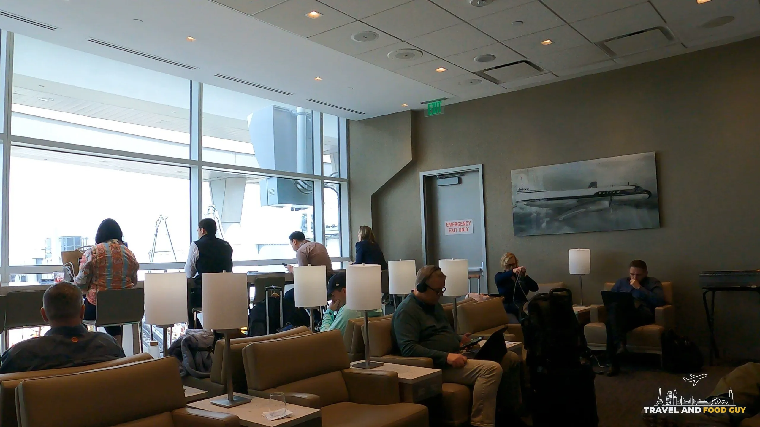 Window seating area at the United Club at DFW with vintage United jet painting
