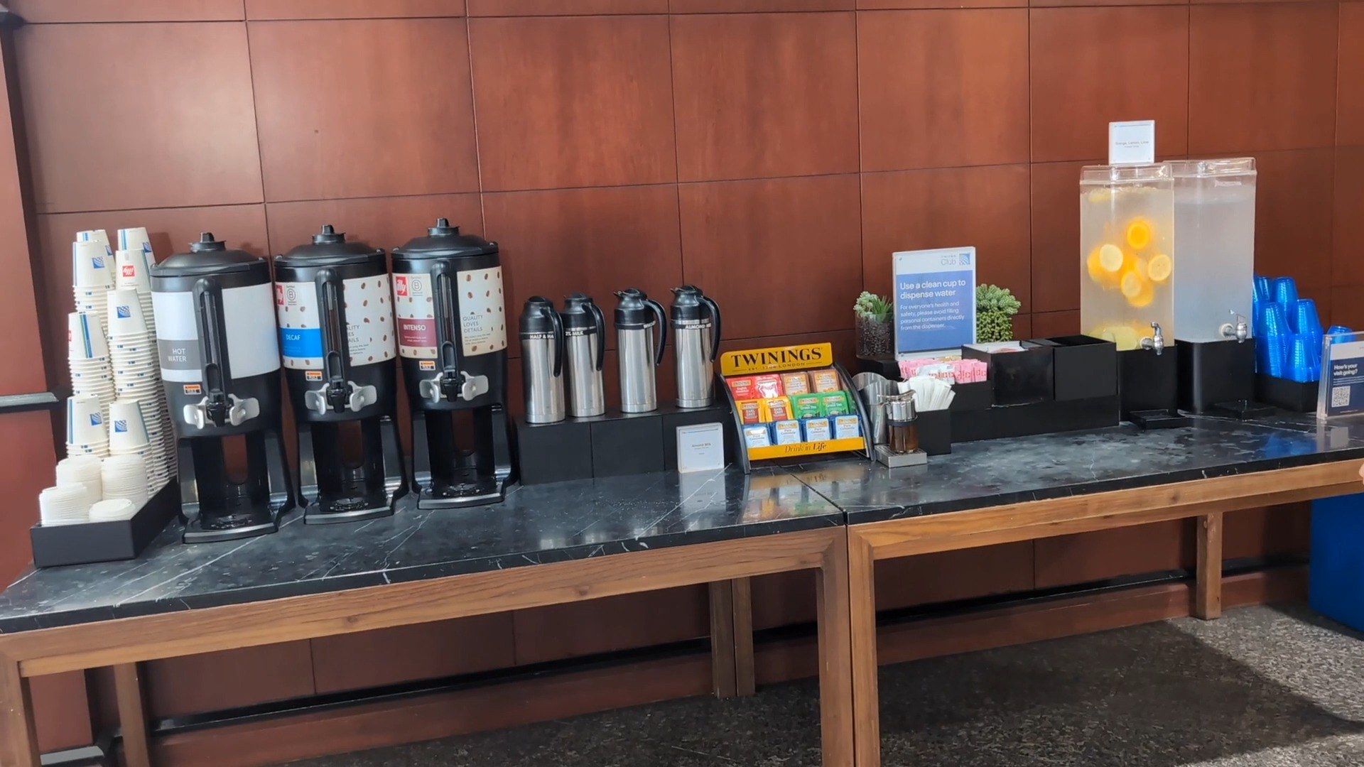 Coffee and tea station at the United Club at IAH Gate C33 with three coffee dispensers, Twinings tea selection, and a fruit-infused water dispenser.
