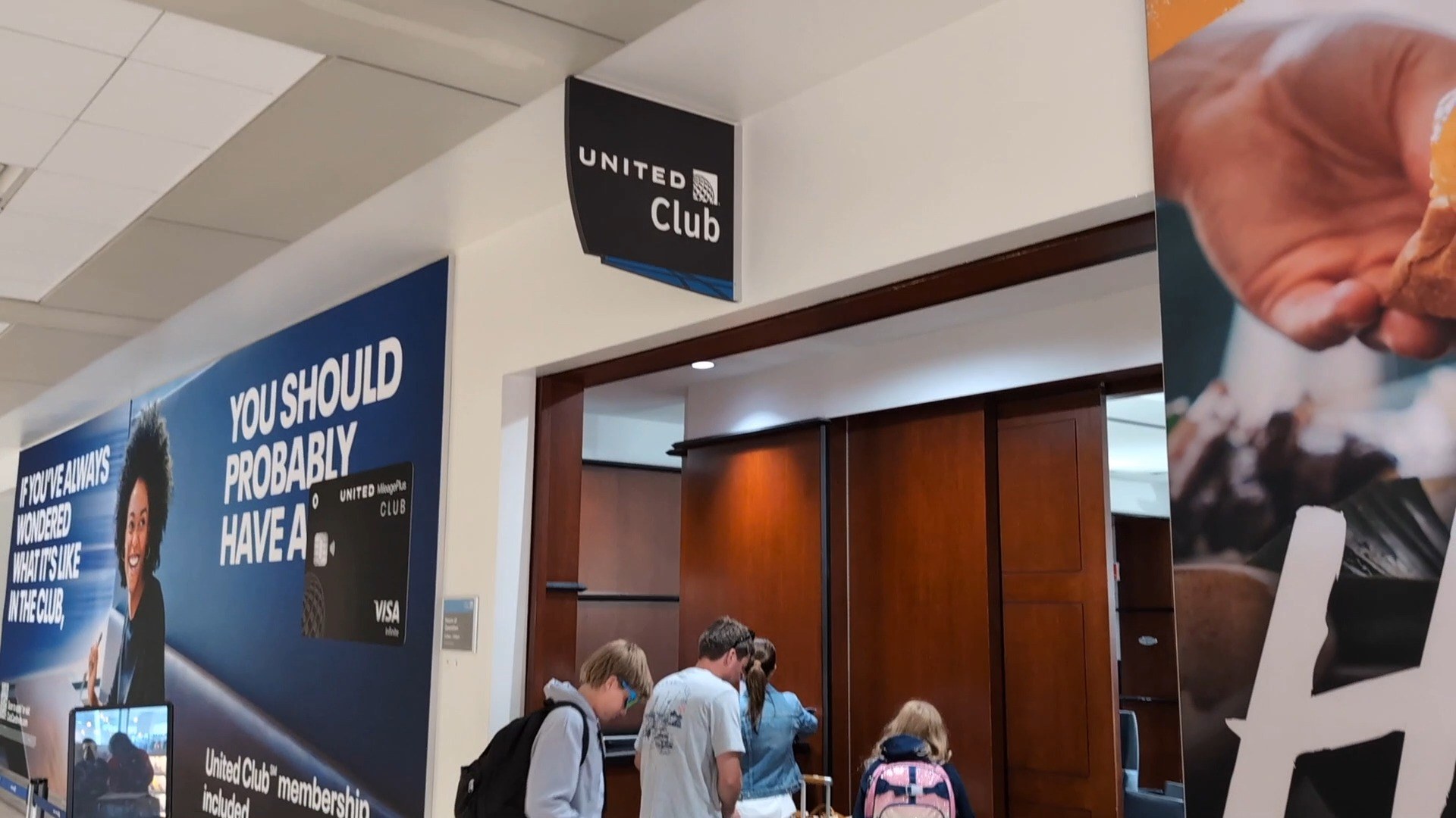 Entrance to the United Club at IAH Gate C33 with the family checking in past the United MileagePlus Club Visa promo wall.