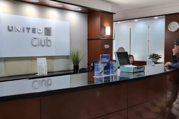 Front desk at the United Club at IAH Gate C33 with the United Club logo on the wall and the wood-paneled lobby behind.