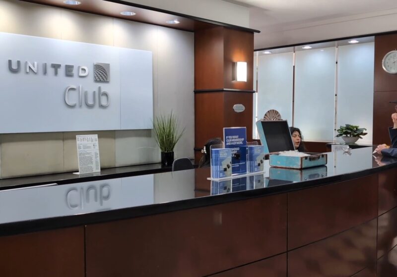 Front desk at the United Club at IAH Gate C33 with the United Club logo on the wall and the wood-paneled lobby behind.