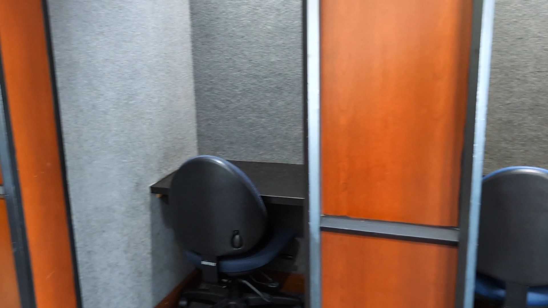 One of the small phone rooms at the United Club at IAH Gate C33, an enclosed work pod with cherry-wood walls and a single desk and chair.