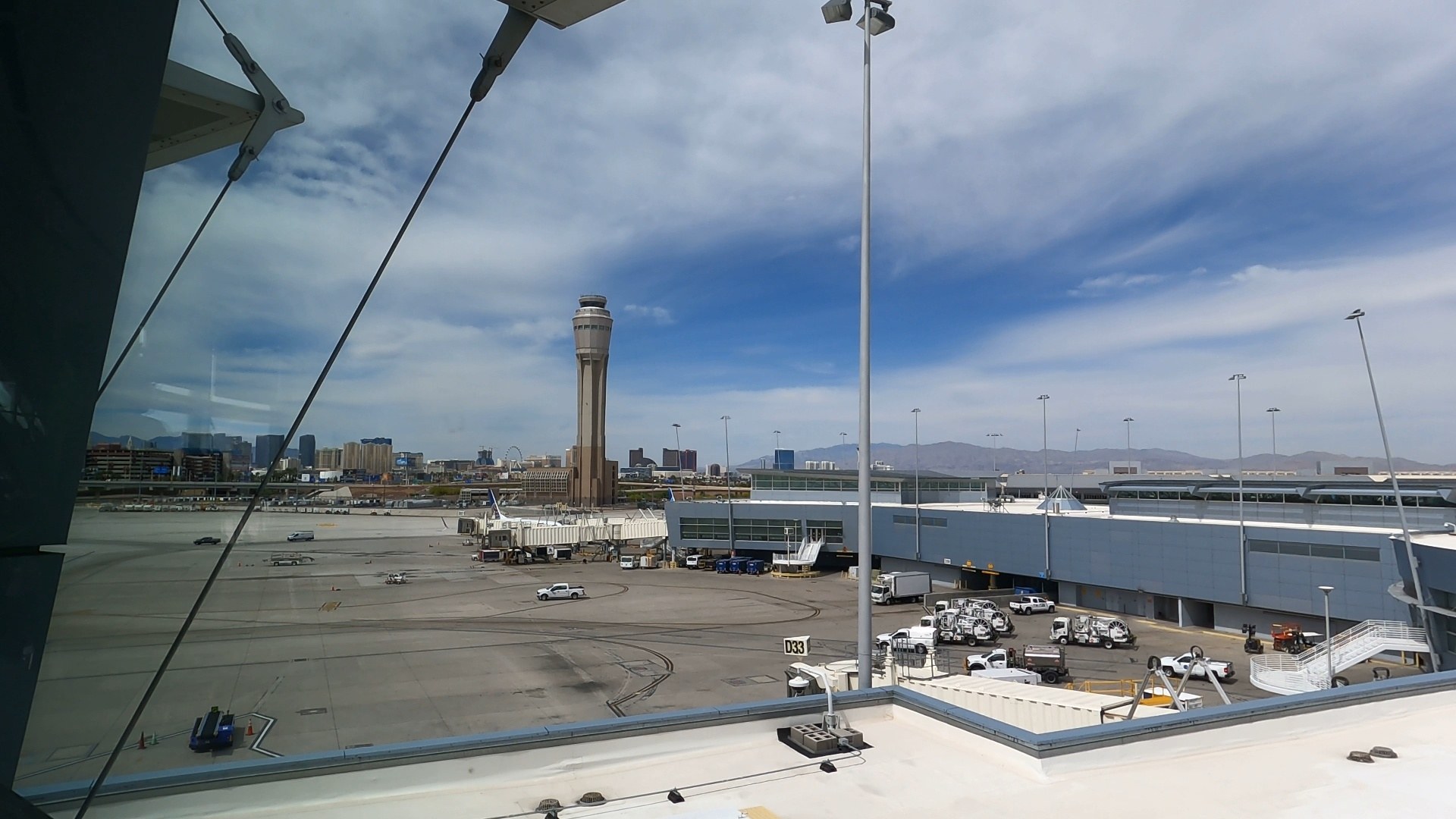 View from the United Club LAS window showing the Harry Reid air traffic control tower and the Las Vegas Strip skyline beyond