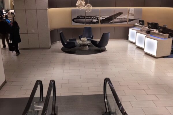 Vintage United Mainliner Convair photo mural behind three black swivel chairs at the United Club at ORD Gate B18, with the illuminated check-in podiums on the right.