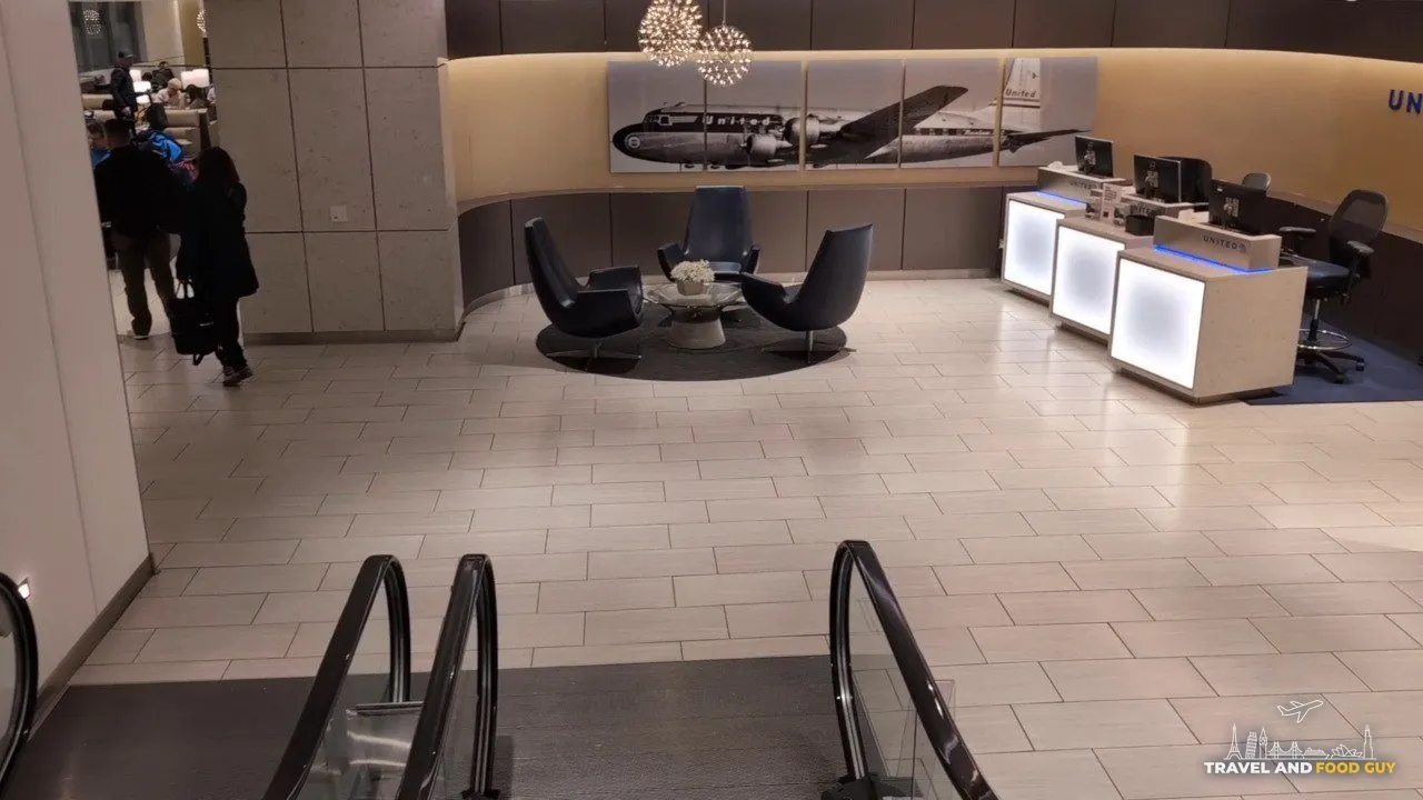 Vintage United Mainliner Convair photo mural behind three black swivel chairs at the United Club at ORD Gate B18, with the illuminated check-in podiums on the right.