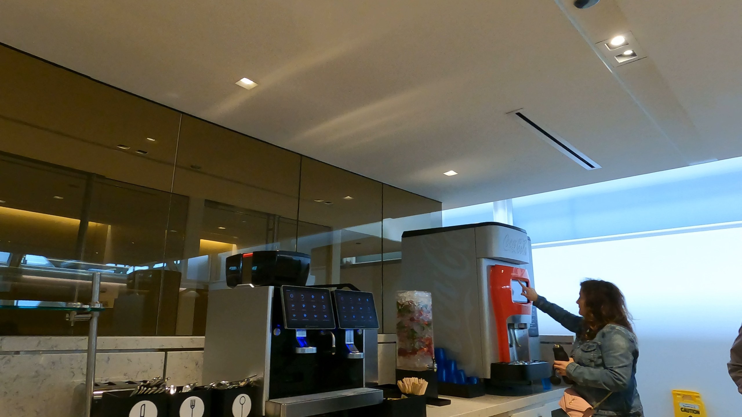 Coca-Cola Freestyle machine and twin automatic espresso machines on the marble counter at the United Club at ORD Gate B6.