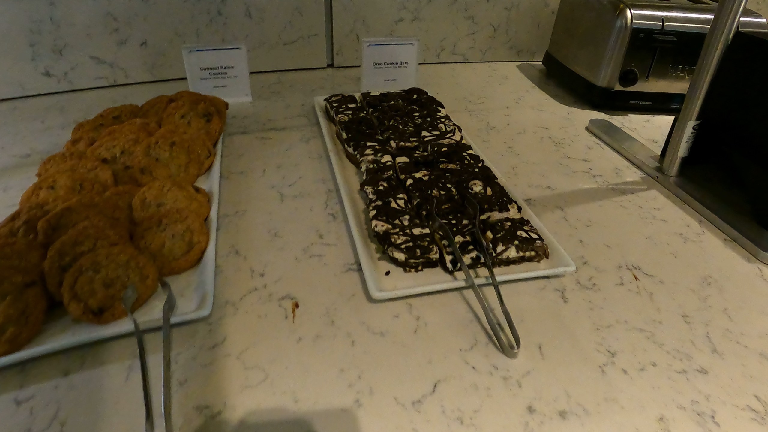 Plates of oatmeal raisin cookies and Oreo cookie bars on the dessert counter at the United Club at ORD Gate B6.