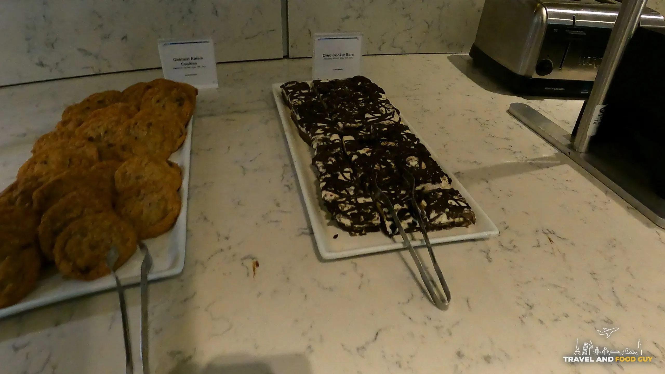 Plates of oatmeal raisin cookies and Oreo cookie bars on the dessert counter at the United Club at ORD Gate B6.