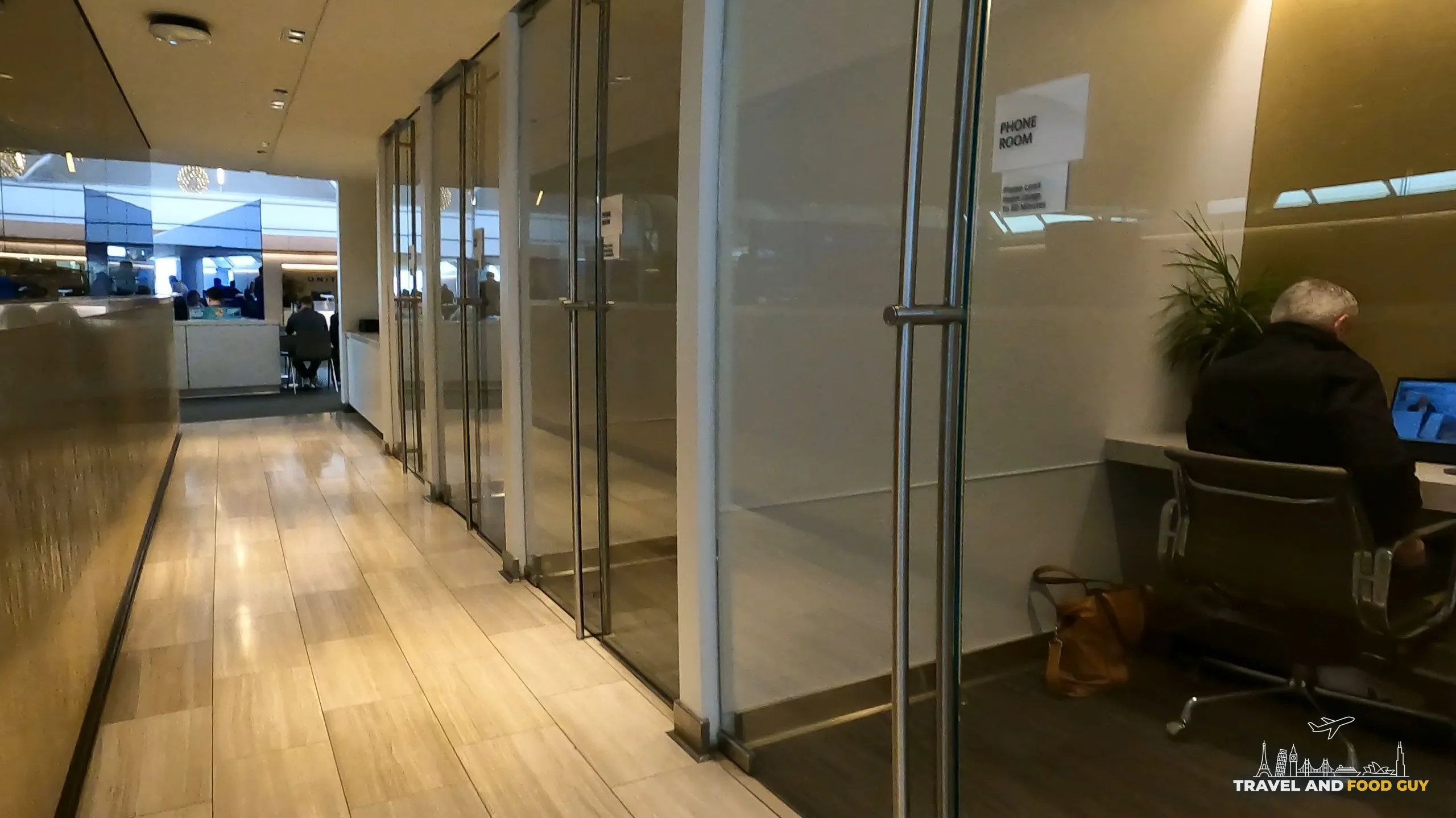Hallway of glass-walled phone rooms at the United Club at ORD Gate B6, each clearly labeled PHONE ROOM and outfitted with a desk and task chair.