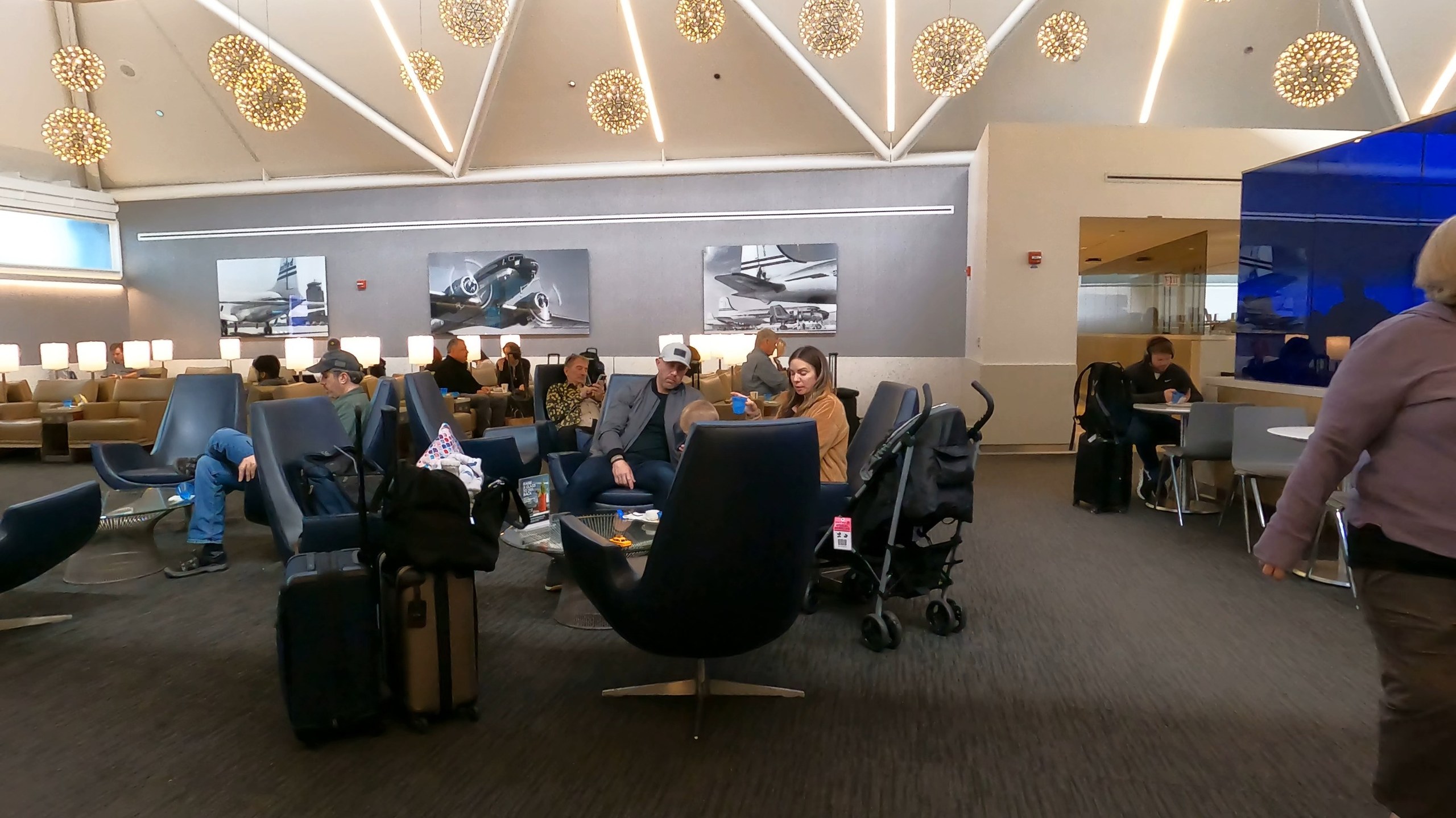 Seating cluster at the United Club at ORD Gate B6 with low-back swivel chairs, side tables, and three black-and-white historical United airplane photographs on the back wall.