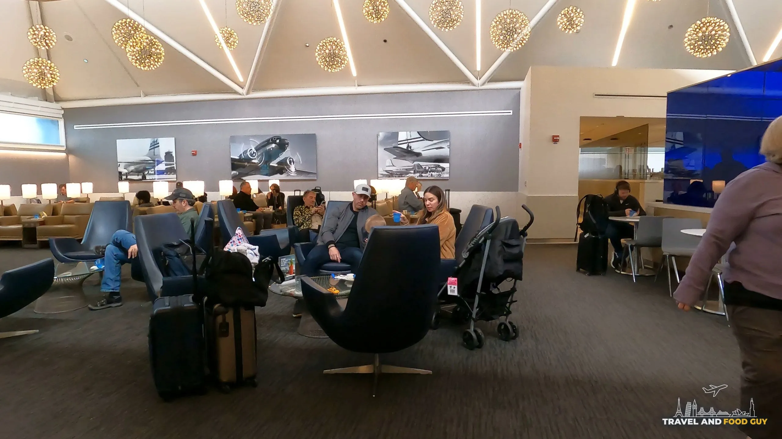 Seating cluster at the United Club at ORD Gate B6 with low-back swivel chairs, side tables, and three black-and-white historical United airplane photographs on the back wall.