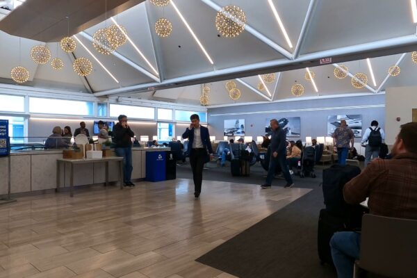 Main seating area at the United Club at ORD Gate B6 with the signature starburst chandeliers overhead, the food counter on the left, and historical United airplane photography on the wall.
