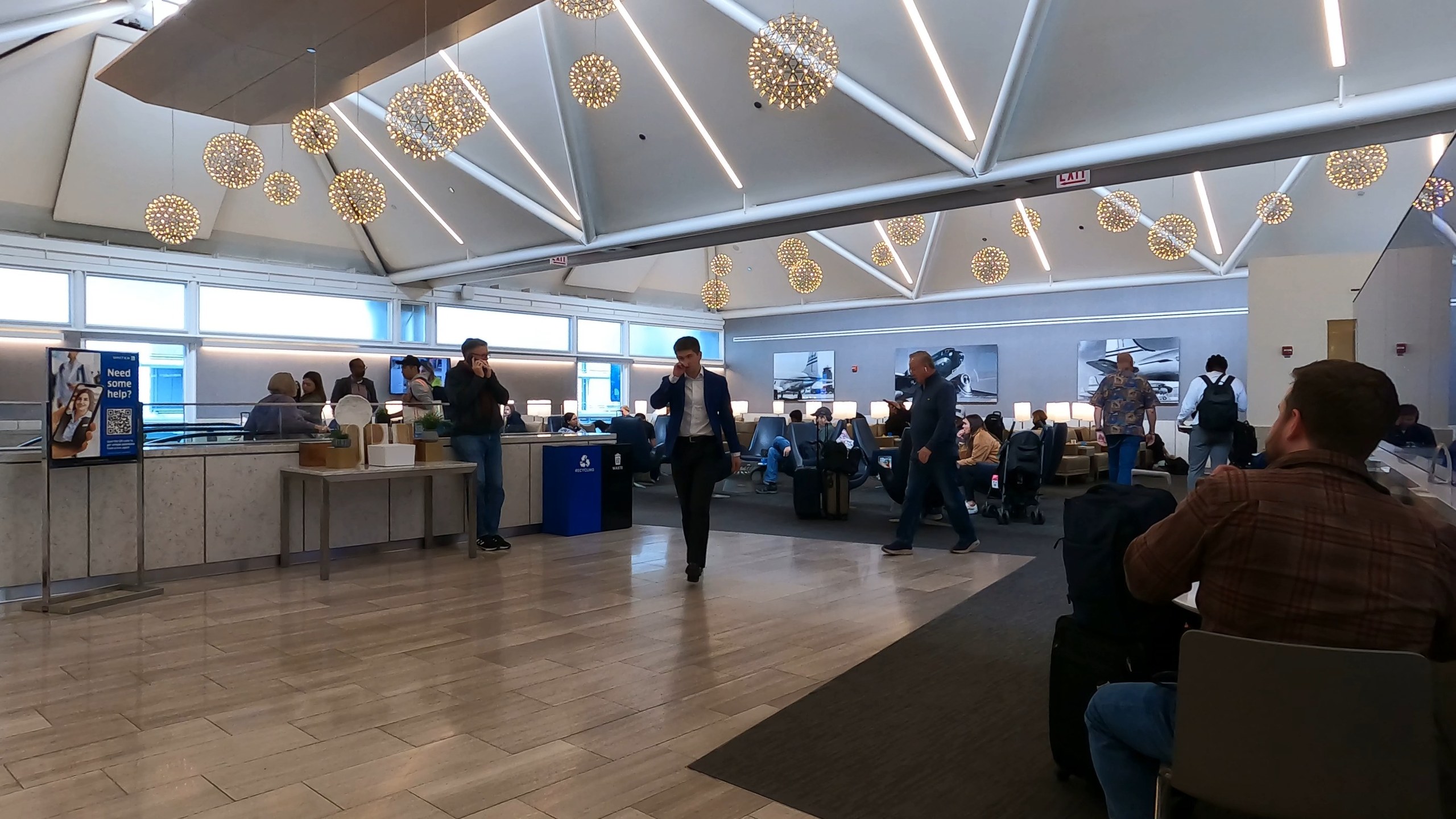 Main seating area at the United Club at ORD Gate B6 with the signature starburst chandeliers overhead, the food counter on the left, and historical United airplane photography on the wall.