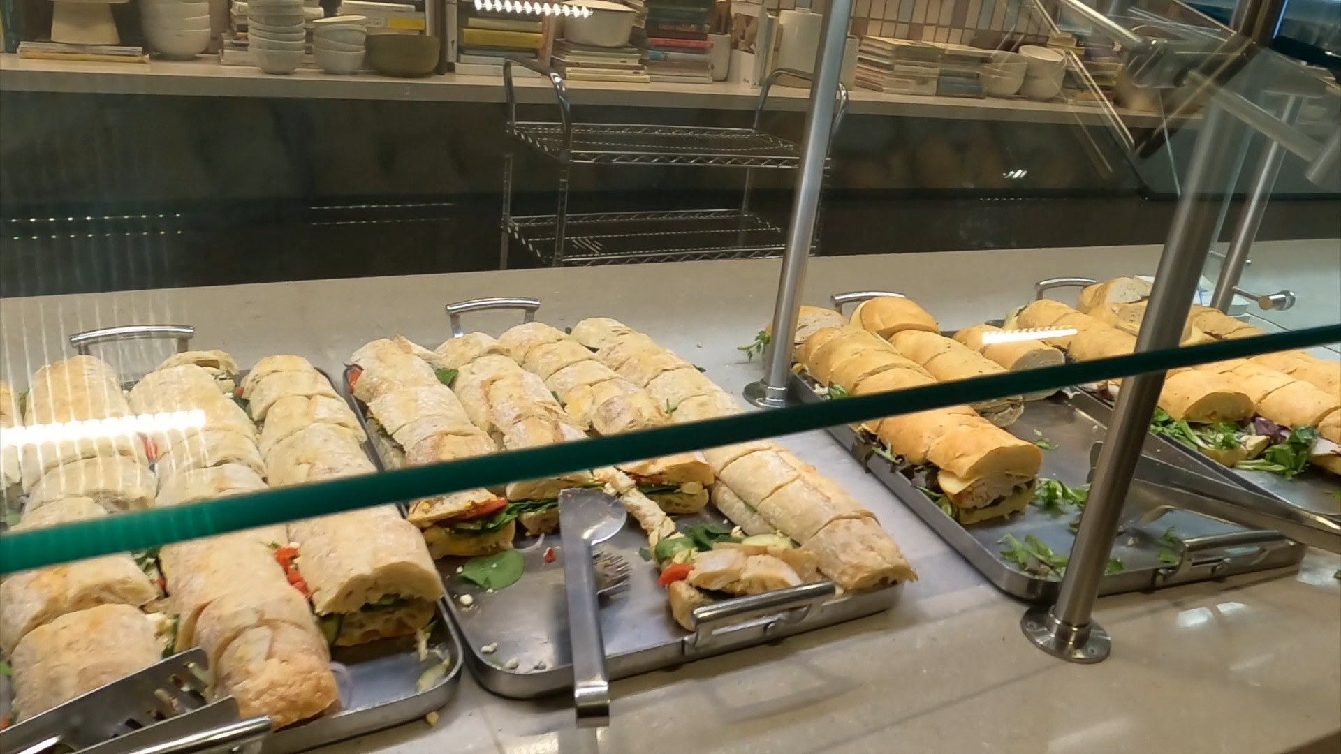 Trays of baguette sandwiches at the United Club at ORD Concourse C, freshly cut and lined up under the buffet glass.