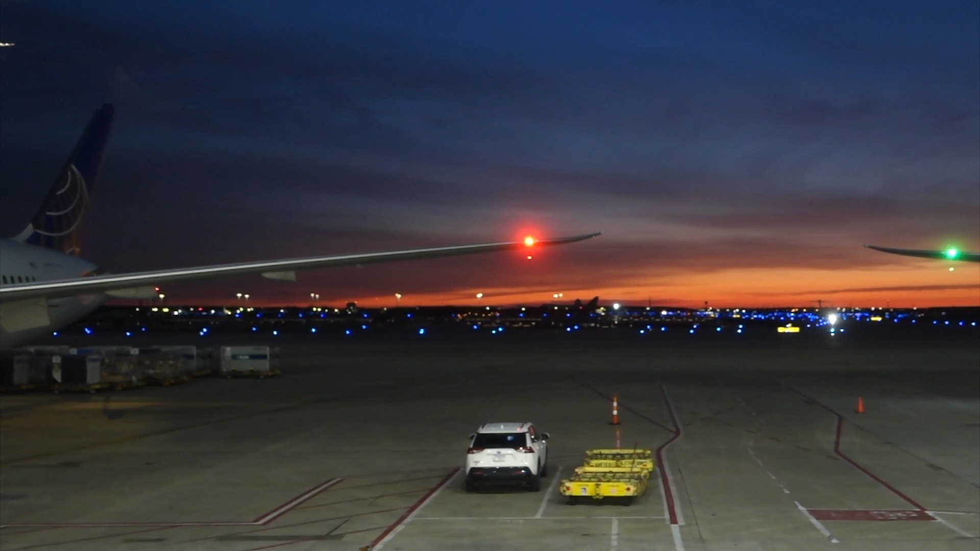 Sunset over the ORD tarmac as seen from the United Club at Concourse C, with a United widebody wing on the left and the runway lights stretching across the distance.
