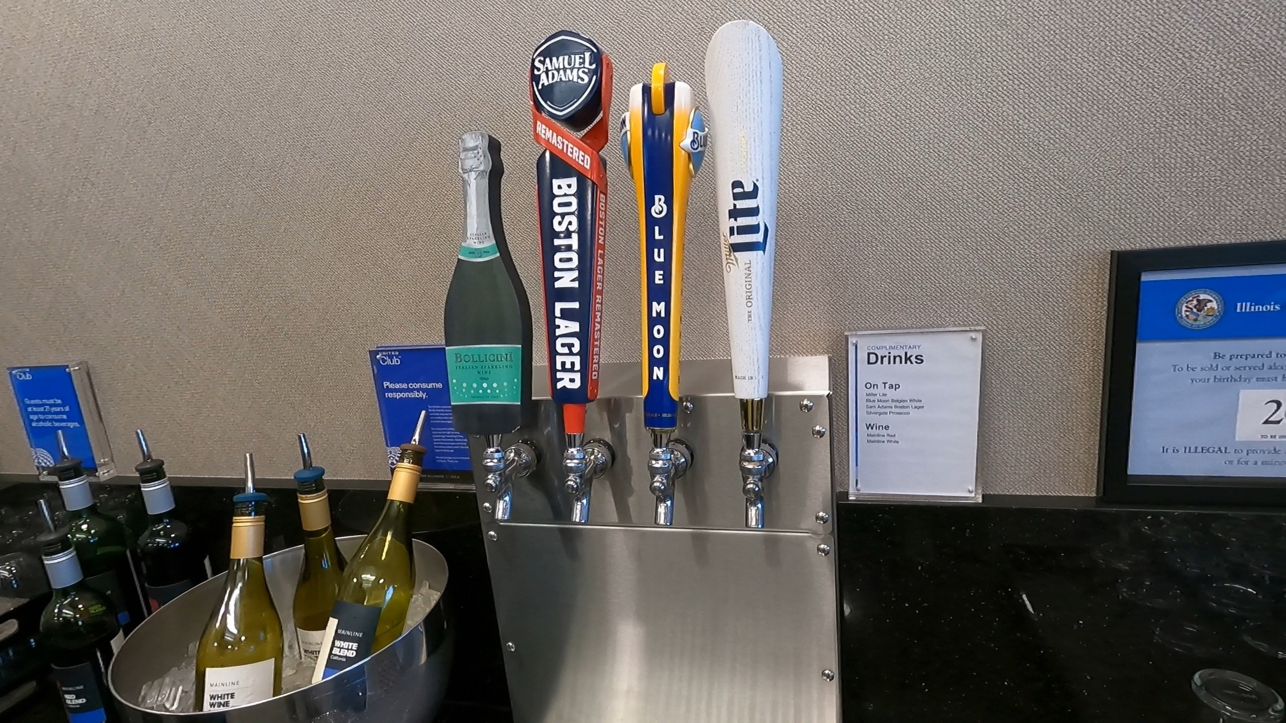 Beer taps at the United Club at ORD Concourse F (Samuel Adams Boston Lager, Blue Moon, Miller Lite) with a champagne bottle and white wines chilling on ice.