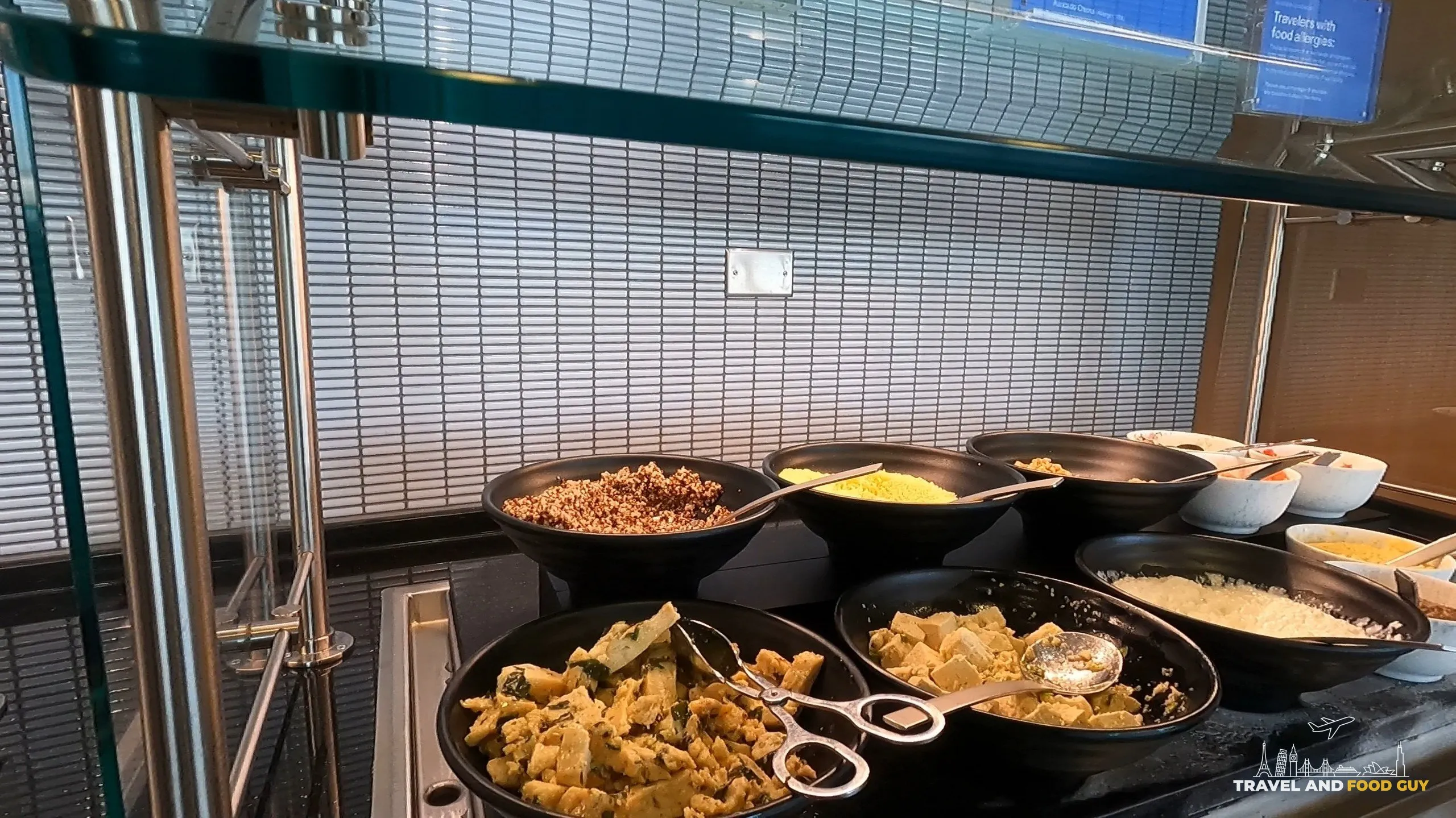 Hot breakfast spread at the United Club at ORD Concourse F with quinoa, scrambled eggs, sausage, oatmeal, and other warm dishes in serving pans.