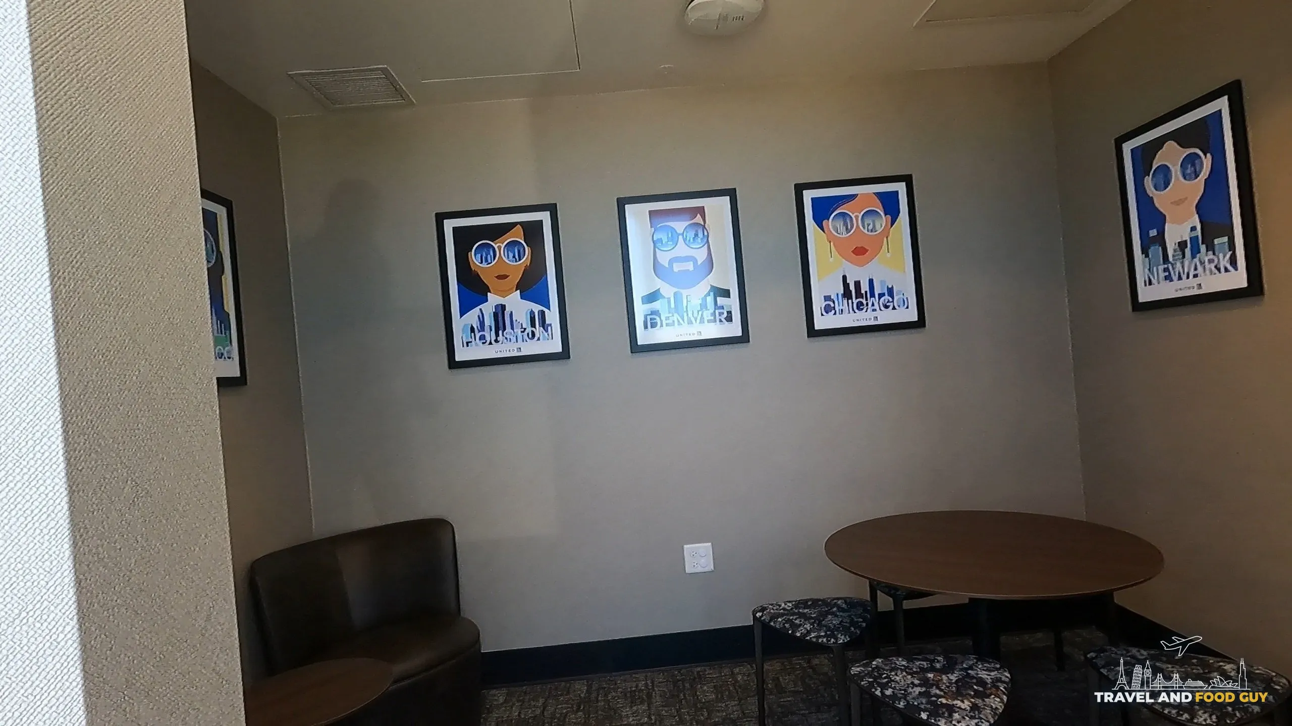Wall of United city posters (Houston, Denver, Chicago, Newark) above a small lounge area at the United Club at ORD Concourse F.