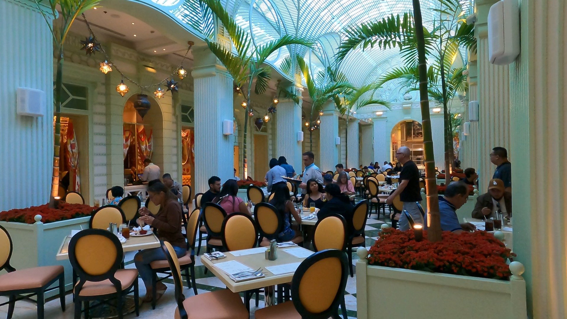 Dining room at The Buffet at Wynn with glass ceiling, palm trees, and yellow leather chairs