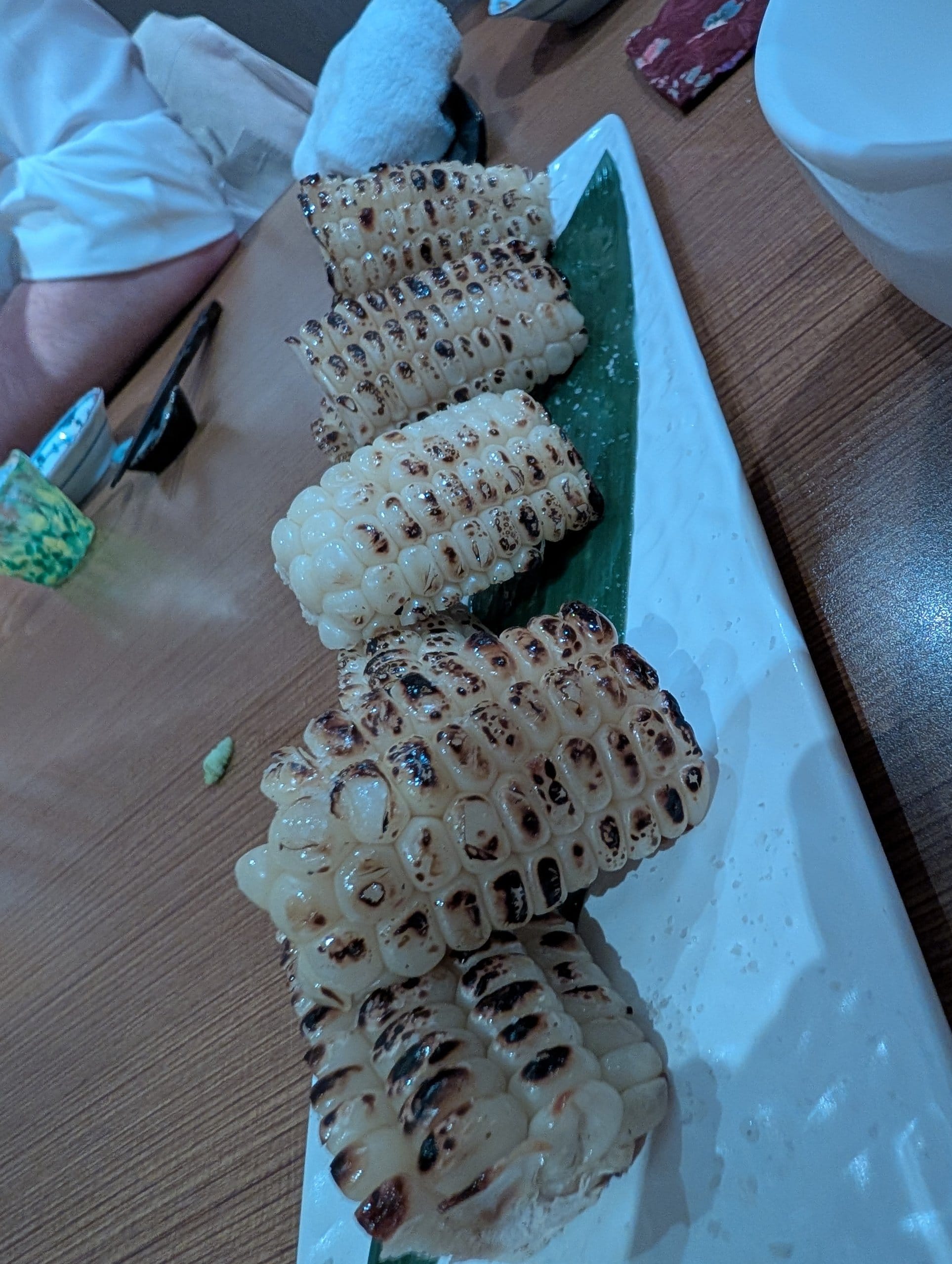 Charred grilled corn cobettes on a long plate at Hanashizuku Singapore