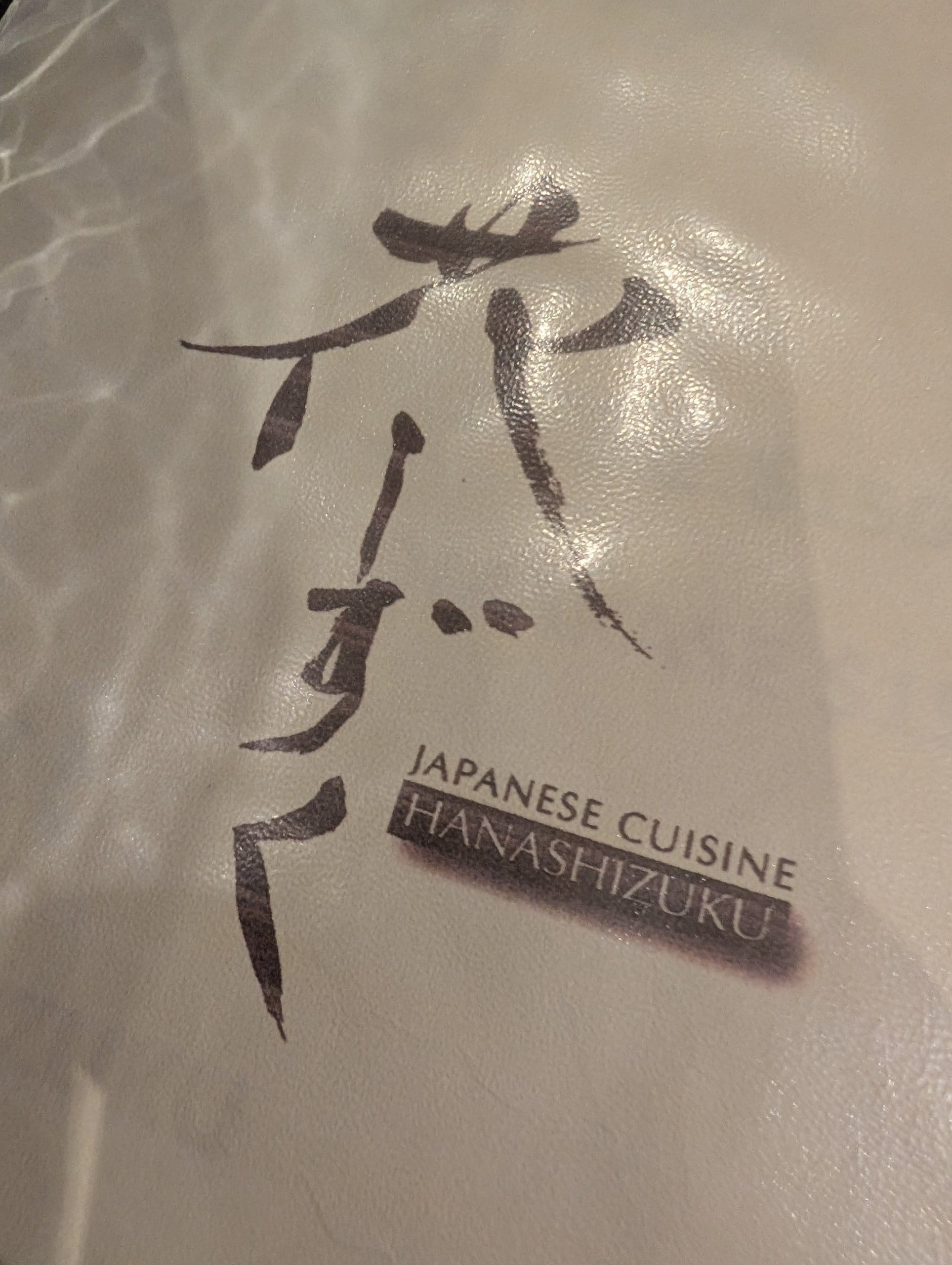 Leather menu cover at Hanashizuku Japanese Cuisine in Cuppage Plaza, Singapore, with kanji and the restaurant name
