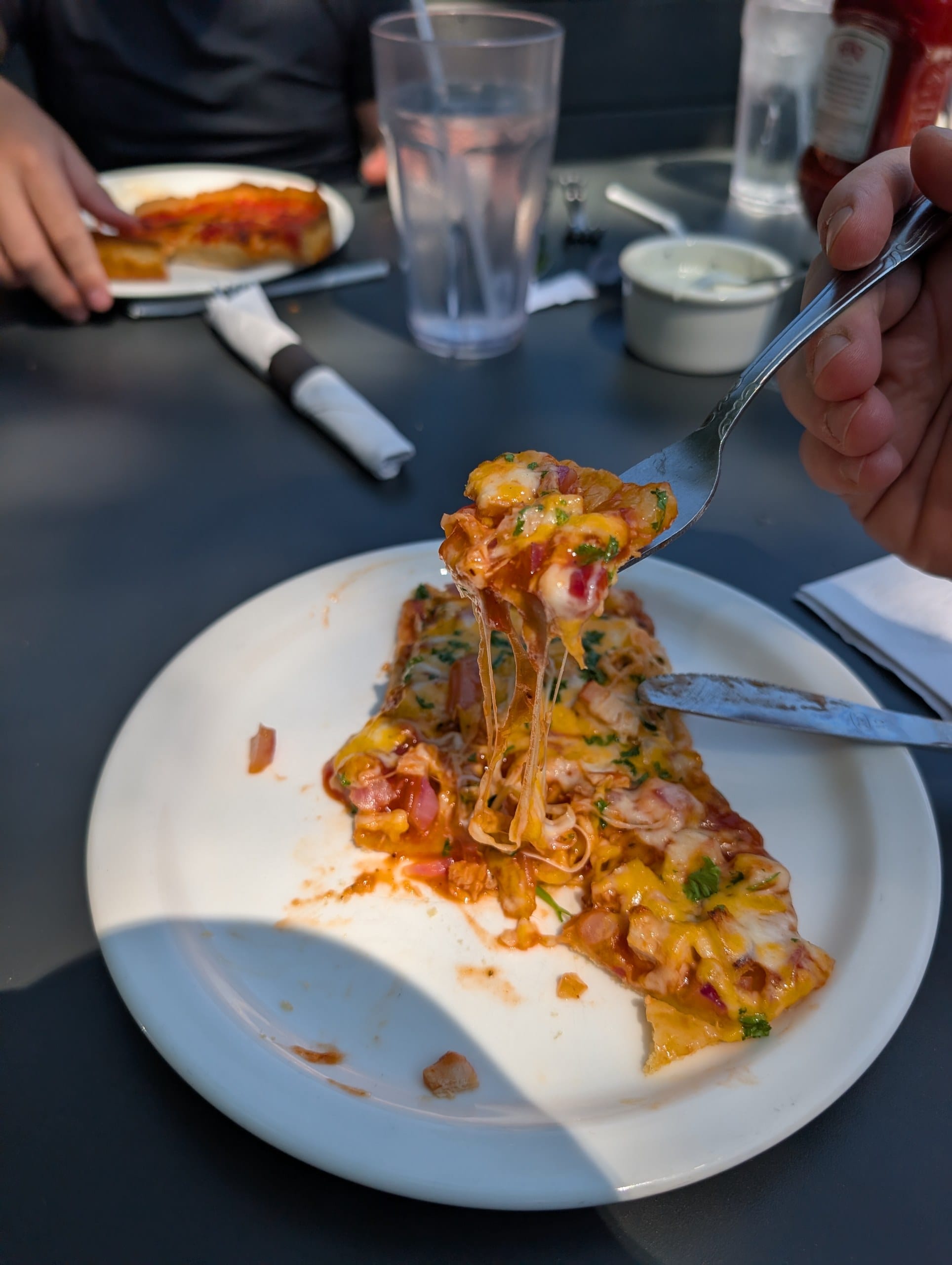 Cheese pull on a forkful of thin crust BBQ chicken pizza at Lou Malnati's Buffalo Grove
