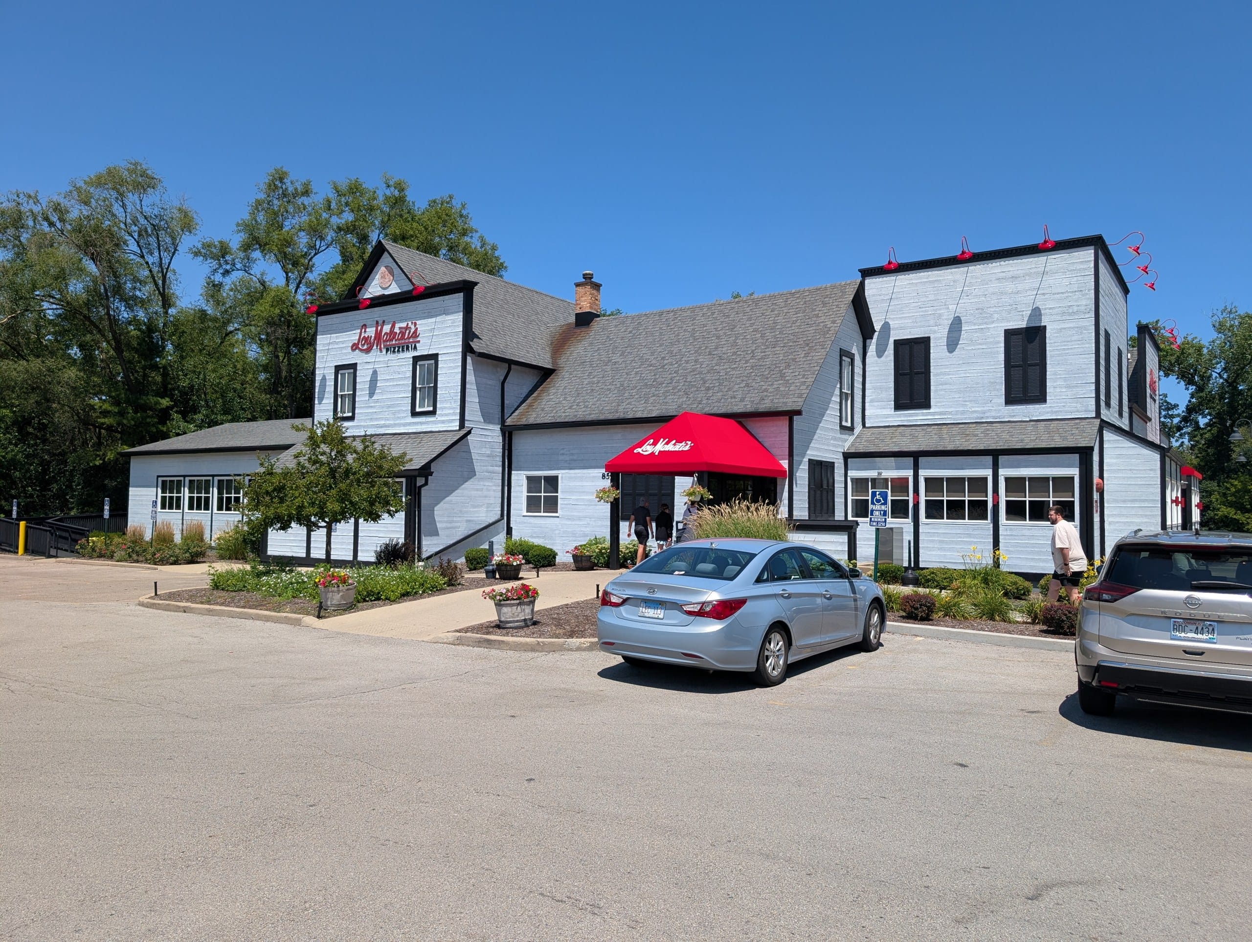 Exterior of Lou Malnati's Pizzeria in Buffalo Grove, a white farmhouse style building with a red awning