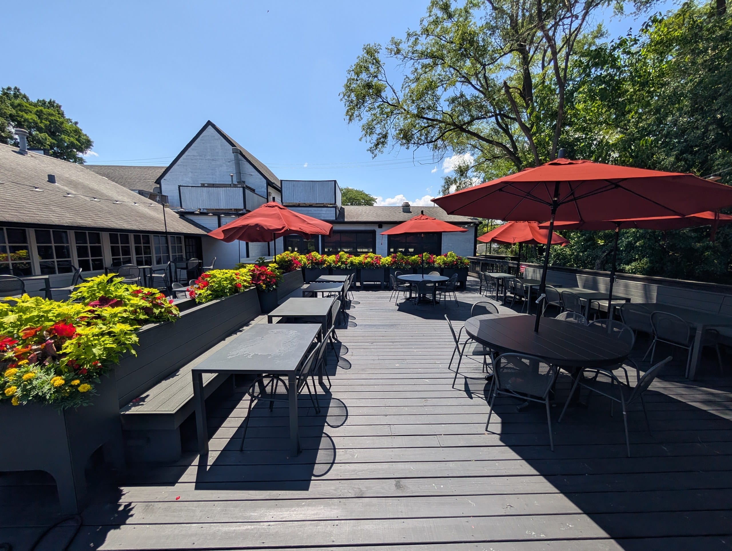 New outdoor patio at Lou Malnati's Buffalo Grove with red umbrellas, flower planters, and bench seating