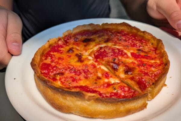 Close up of a Lou Malnati's personal deep dish cheese pizza with tomato sauce on top and golden Buttercrust.