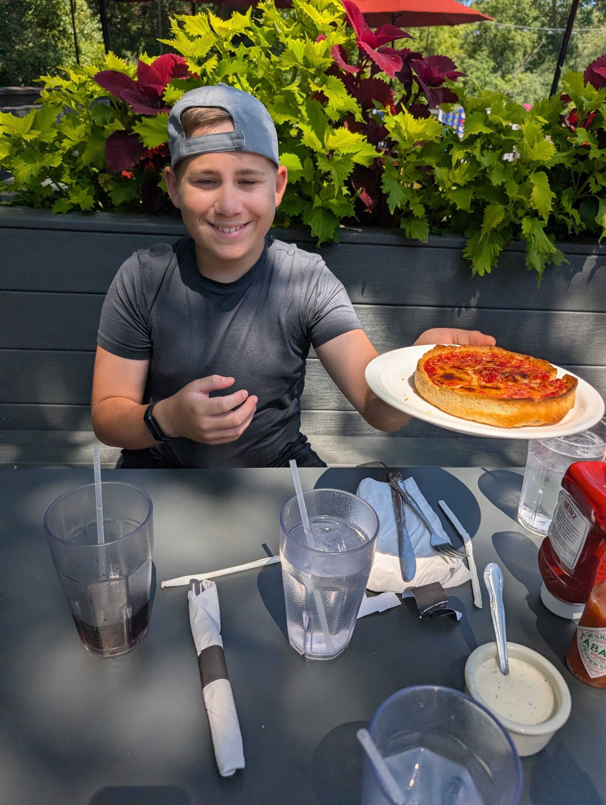 Teenager holding a personal deep dish pizza on the patio at Lou Malnati's Buffalo Grove