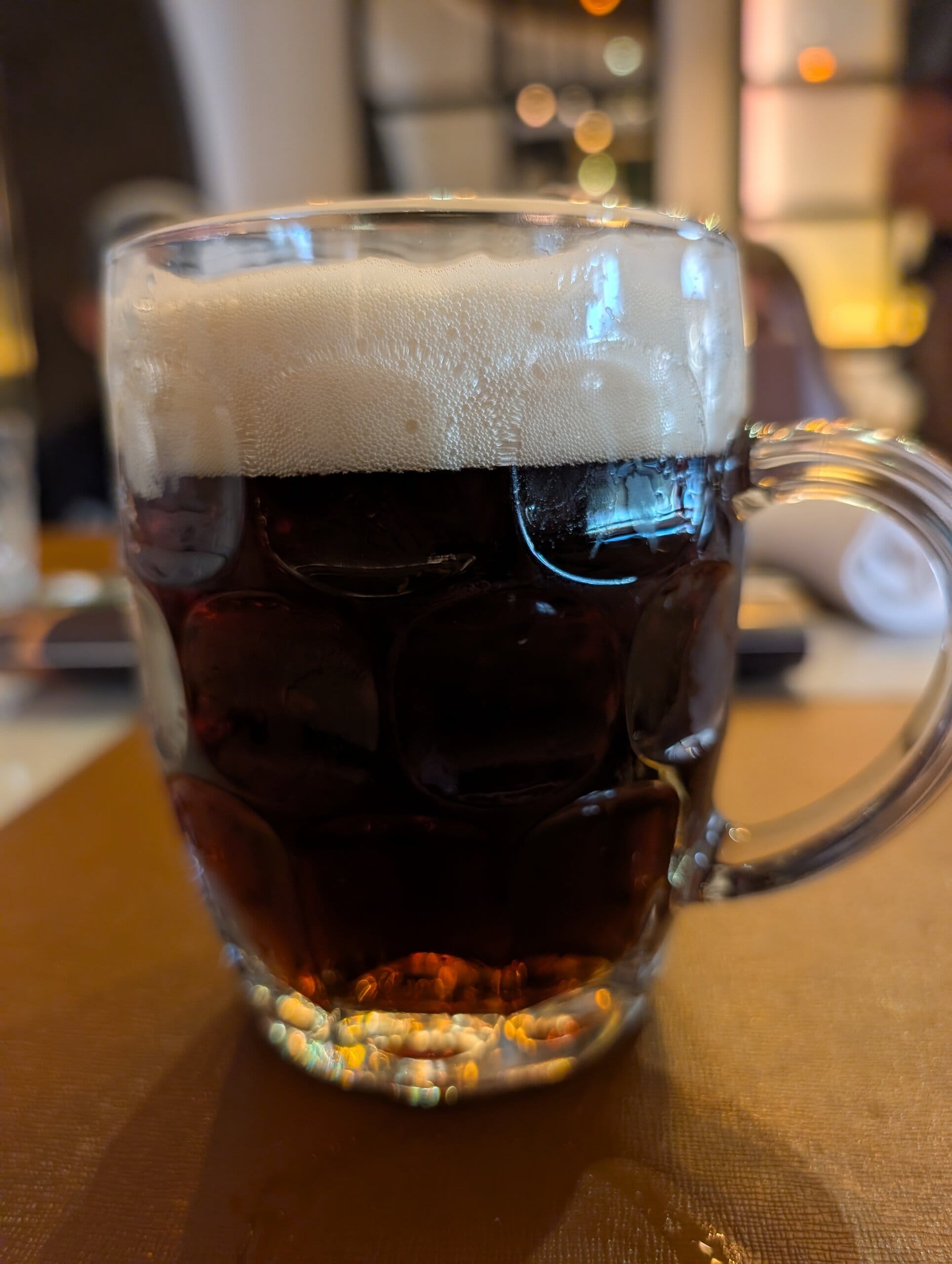 Cold dark beer in a dimpled mug at Mylord in Civitavecchia