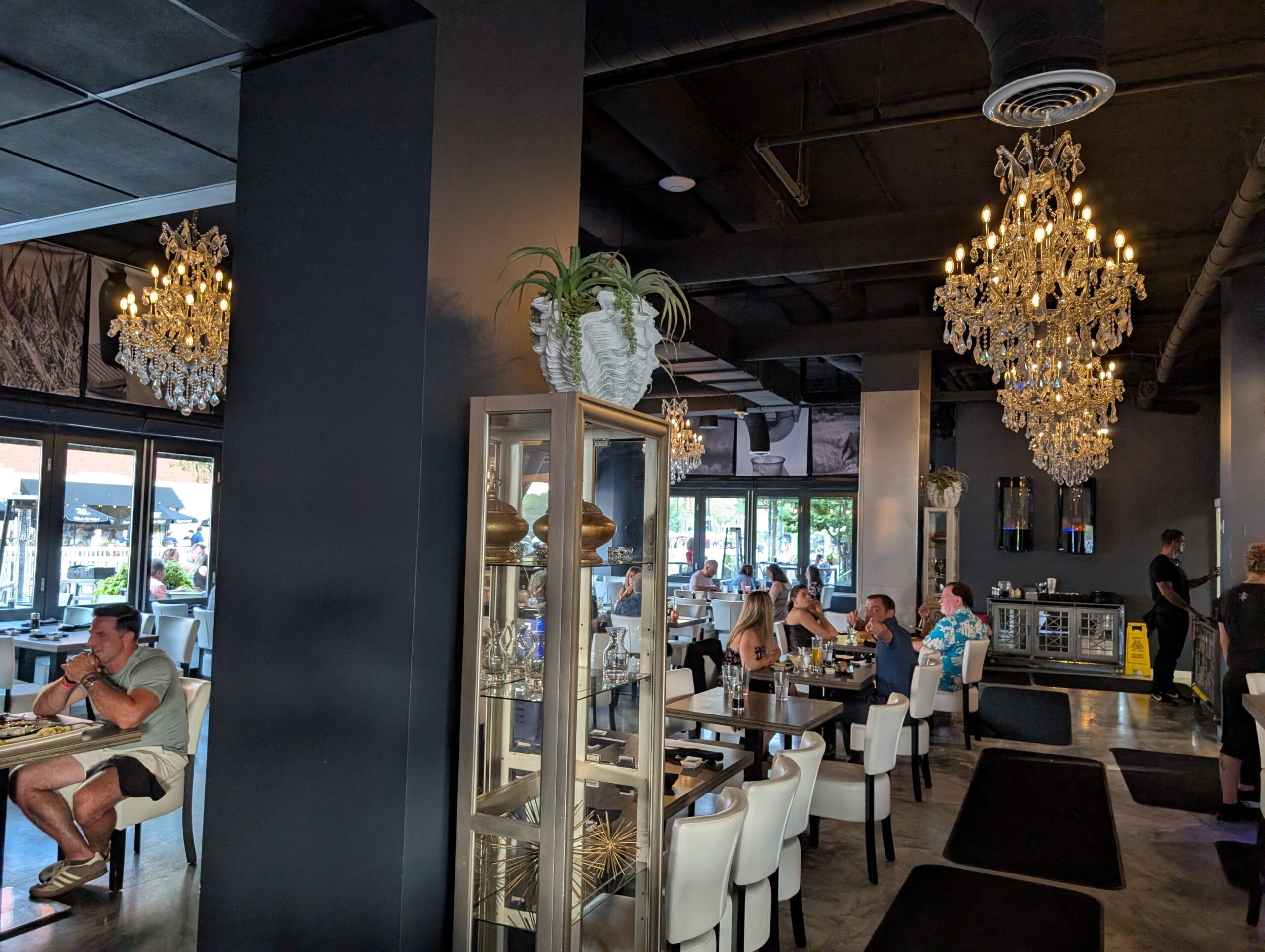 Shakou Arlington Heights dining room with crystal chandeliers, dark walls and white leather chairs