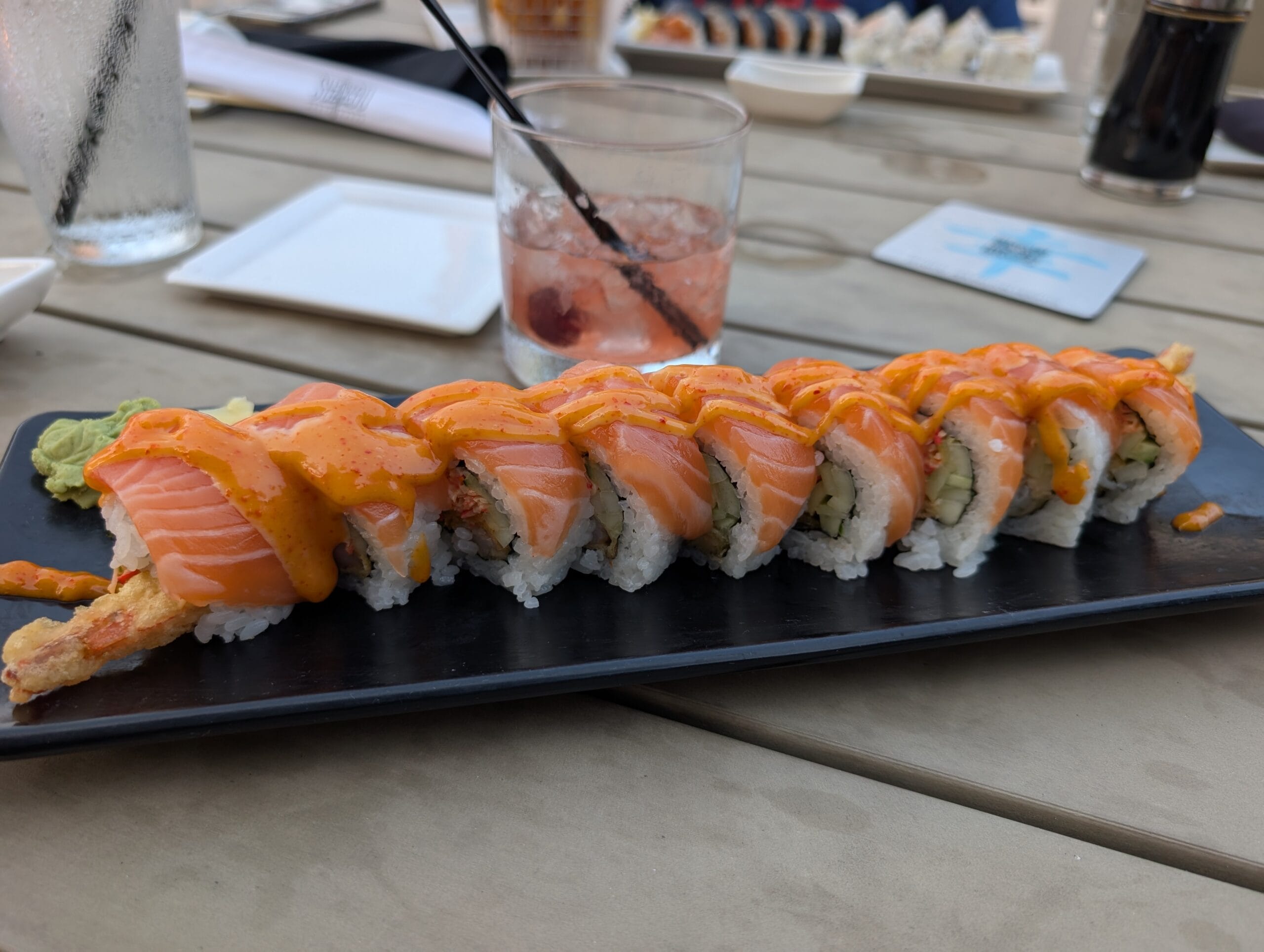 Hikaru signature roll at Shakou Arlington Heights topped with fresh salmon and spicy mayo on a black plate